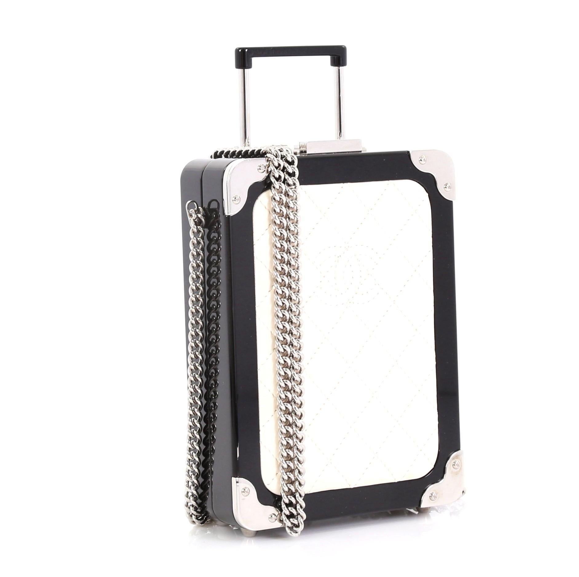 This Chanel Trolley Minaudiere Plexiglass and Quilted Lambskin, crafted from black plexiglass and white quilted lambskin leather, features chain-link crossbody strap, rolling suitcase silhouette, Chanel CC logo stitched in the center and silver-tone
