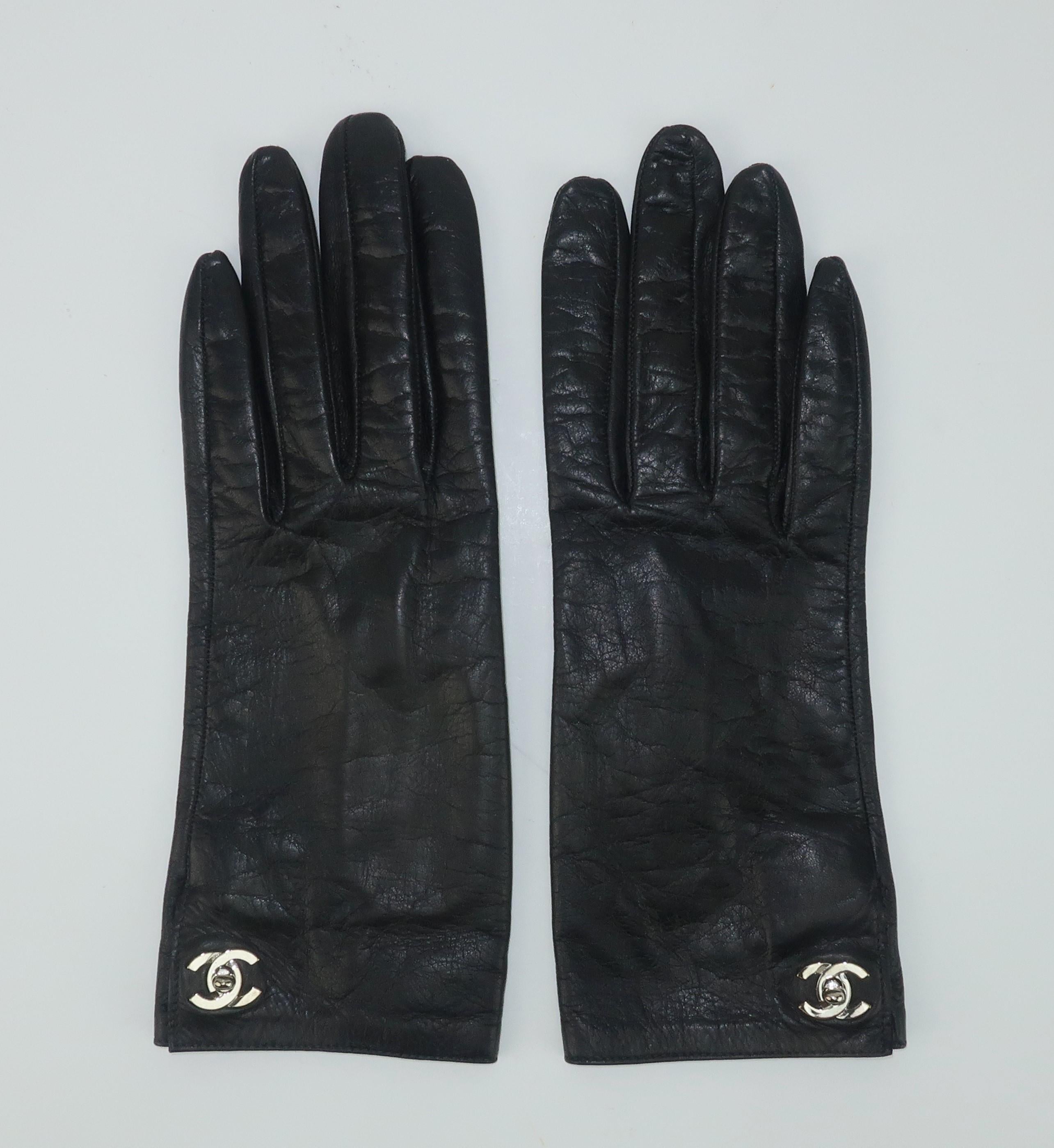 Chanel black leather gloves with a unique silver logo turn lock closure at the wrist.  Lined in silk and accompanied by the original box with felt cloth.
CONDITION
Very good condition with some light indications of previous wear.  The box shows wear