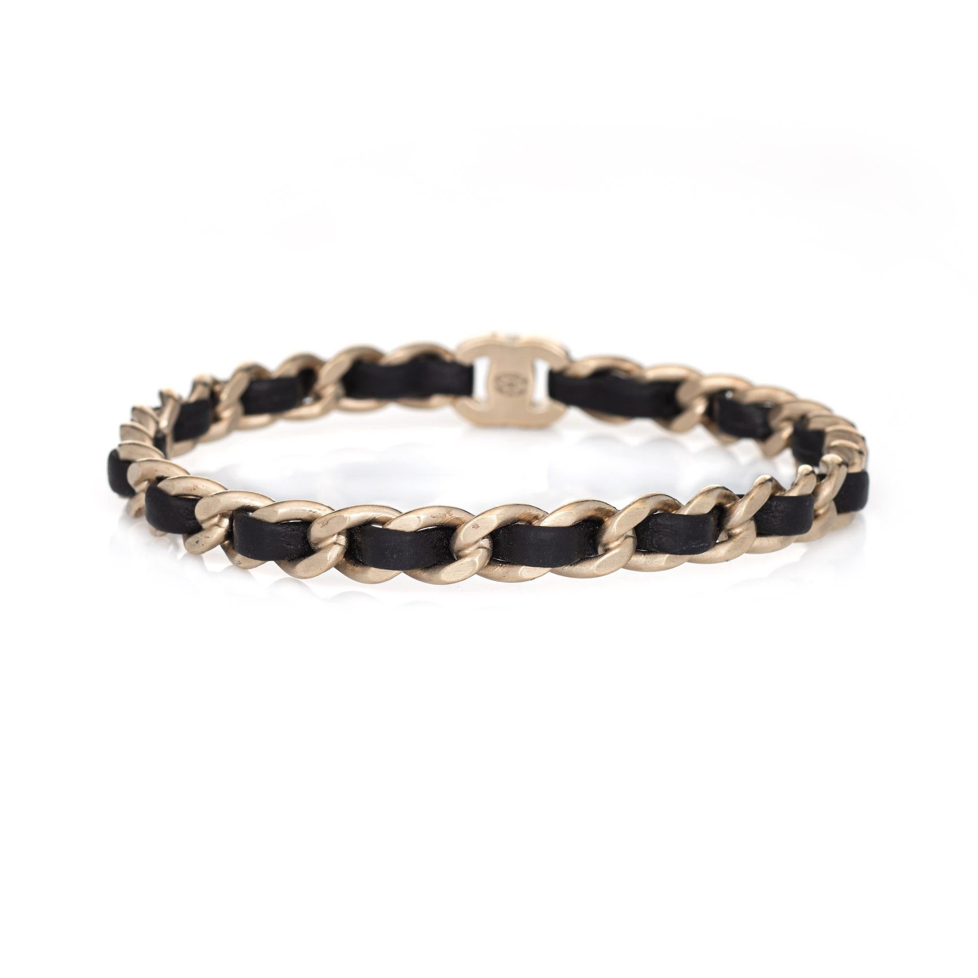 Pre-owned Chanel turnlock chain link leather bangle bracelet (circa 2012). 

The chic bracelet features a light yellow gold matte finish with black leather laced through the chain-link, along with the turnlock CC logo.

The bracelet is in good