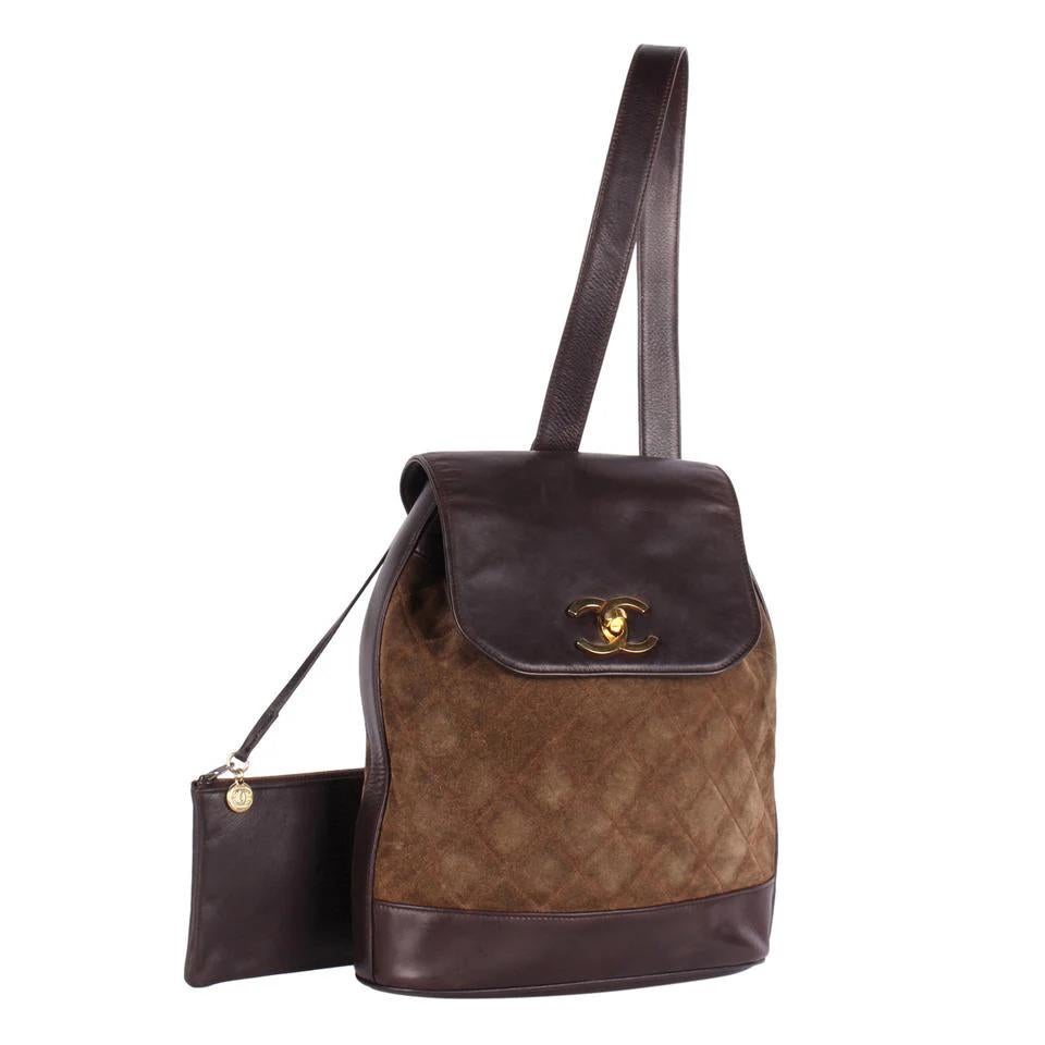 Authentic, pre-owned Chanel brown turn-lock brown leather and suede one-shoulder slingback backpack. Features suede, leather accents, large interior with a zipped slip pocket and an attached pochette for your cosmetics or use as a wallet, 24 kt gold