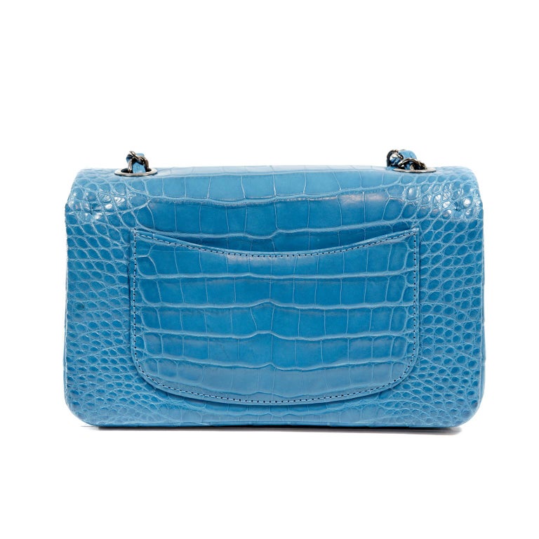 This authentic Chanel Turquoise Blue Matte Alligator Small Classic Flap is in pristine condition.  Rare matte alligator skin makes this exotic piece truly collectible.
Beautiful turquoise matte alligator skin is accented with sophisticated silver