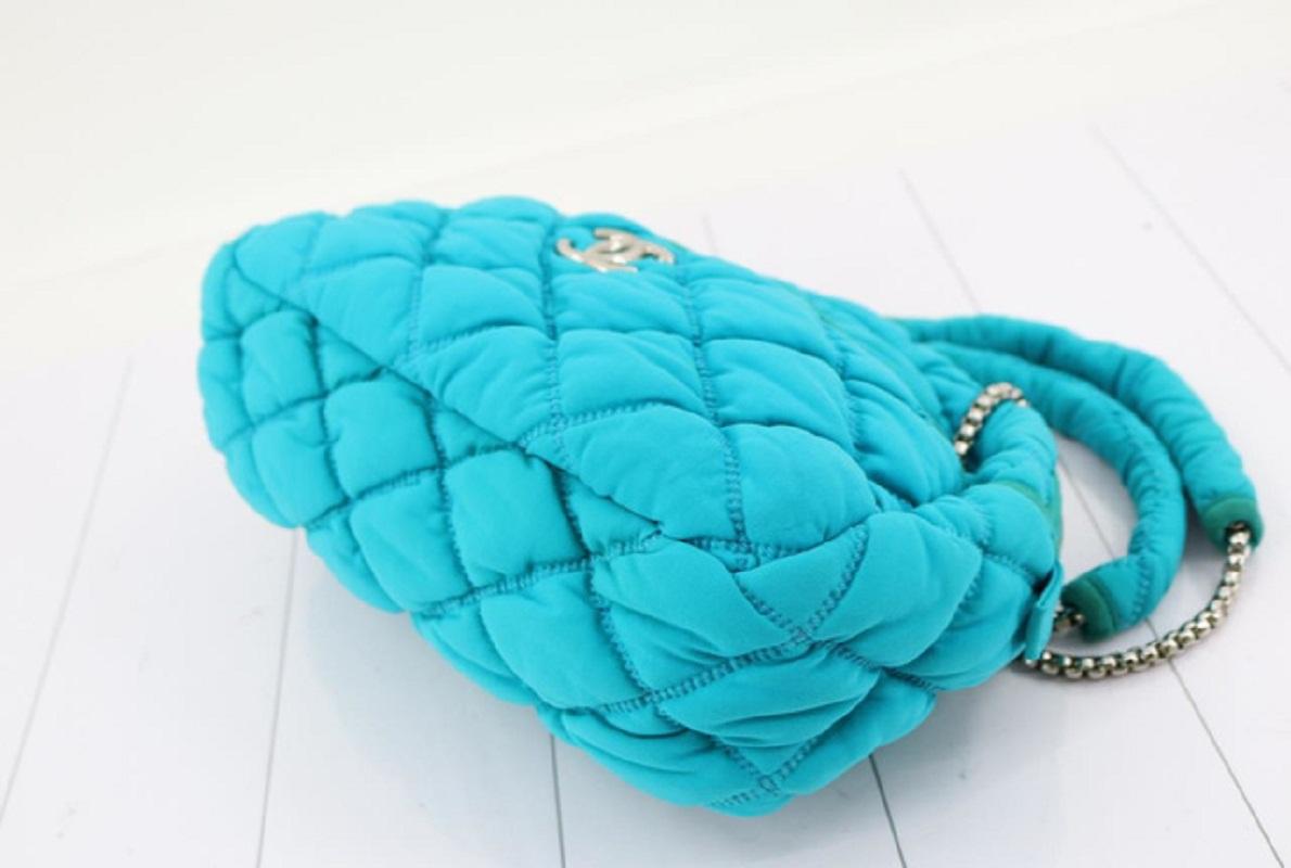 Chanel Turquoise Quilted Bubble Jersey Snake Effect Chain shoulder bag is crafted in a quilted pattern, this bag features a fabric shoulder pad with snake-effect chain link straps in silver-tone hardware. The full zipper closure opens to a finely