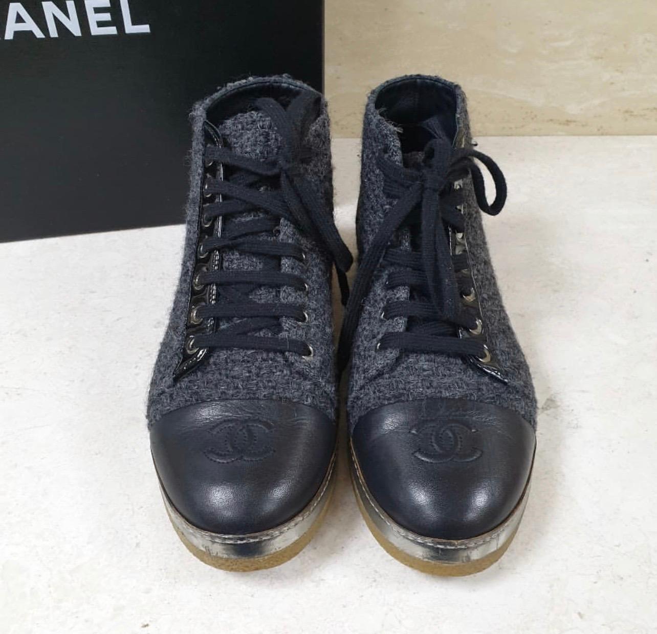 A blend of style and bold simplicity, these ankle boots from Chanel will sweetly complement your casual as well as evening ensemble. 
Crafted with a grey wool blend, the boots have leather cap toes carrying the CC stitch details and lace-ups at the