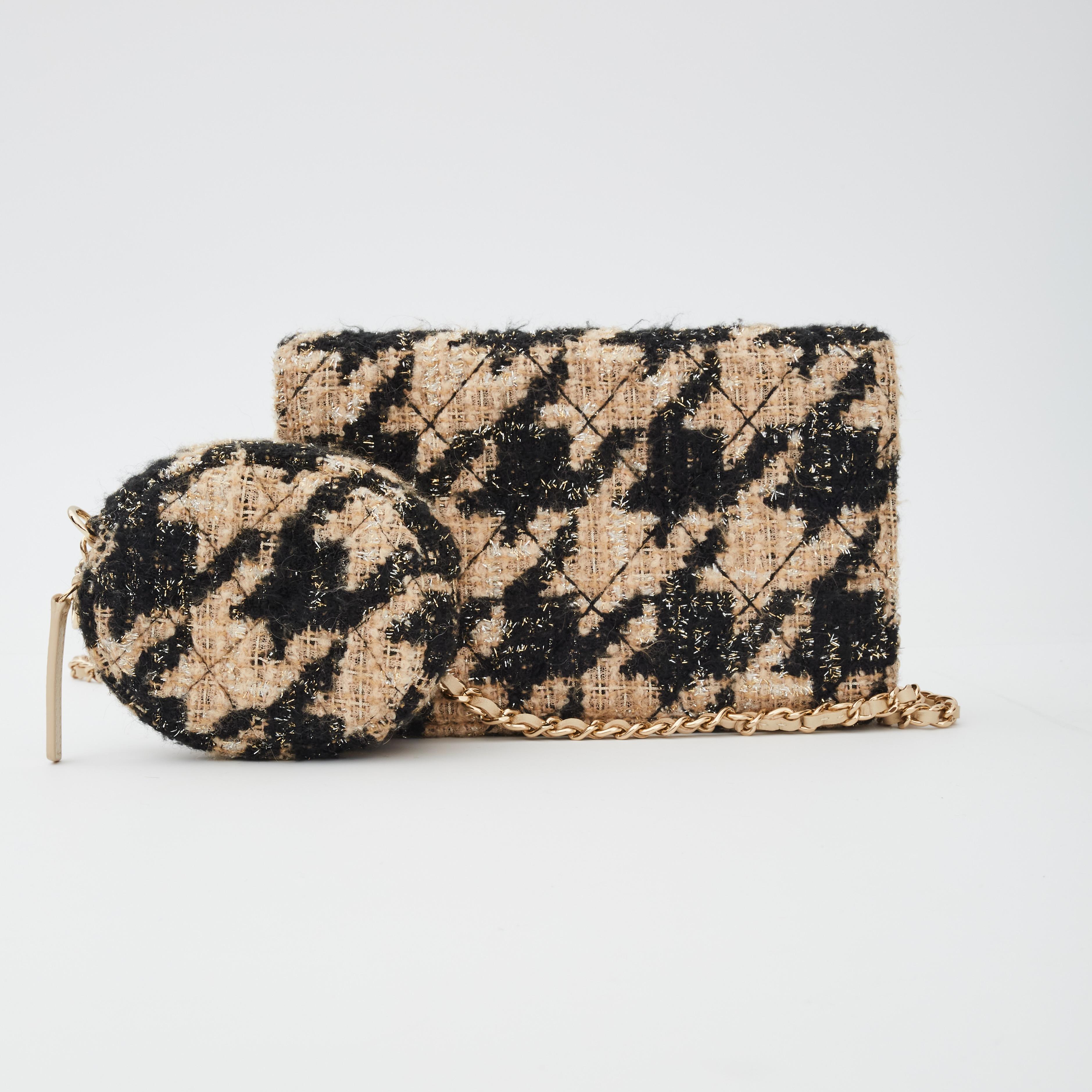This crossbody bag is made of diamond quilted tweed shearling in black and beige. The bag features a shoulder strap of a light gold chain interlaced with leather, a matching black Chanel CC logo on the front, a removable coin purse, a front flap