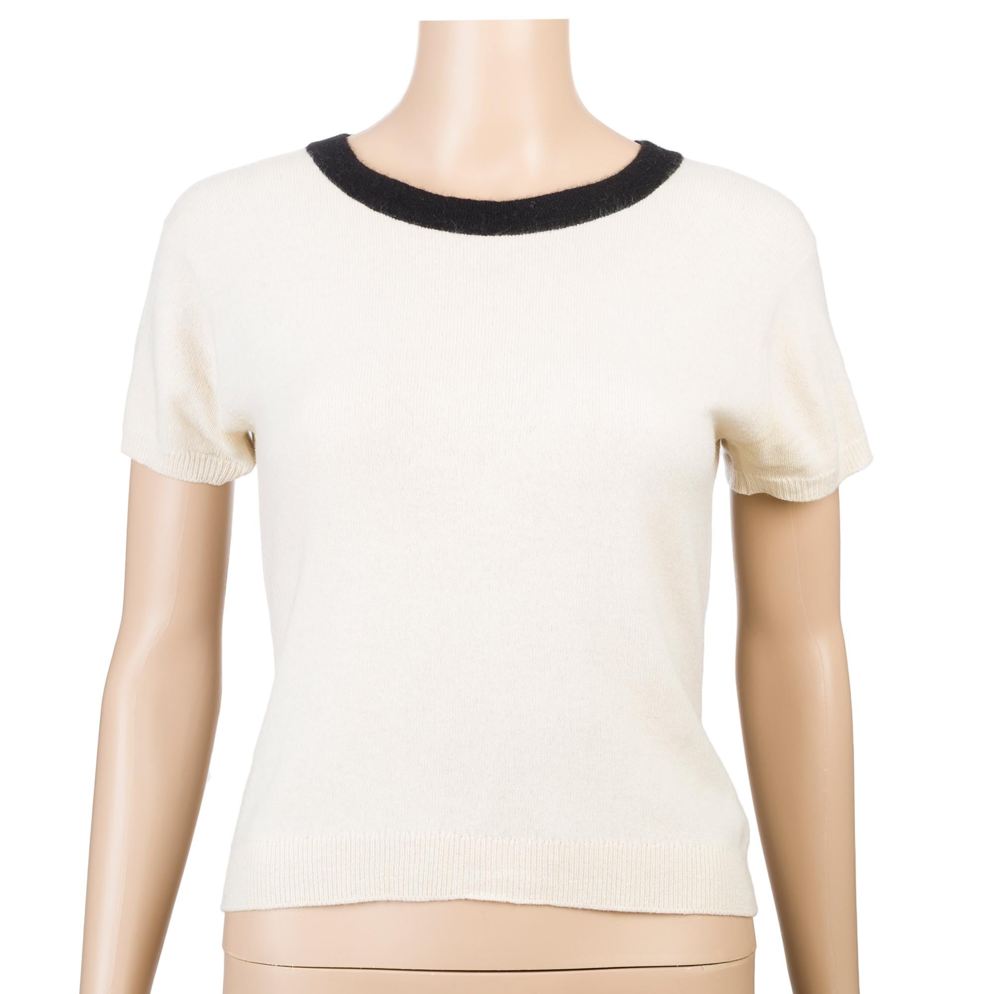 This​ ​sumptuous​ ​Chanel​ ​twinset​ ​in​ ​creme​ ​cashmere​ ​consists​ ​of​ ​a​ ​short-sleeved​ ​top​ ​with​ ​a​ ​contrasting​ ​black​ ​crew​ ​neck,​ ​and​ ​a​ ​matching​ ​cardigan​ ​enhanced​ ​with​ ​black​ ​trim.​ ​The​ ​cardigan​ ​features​