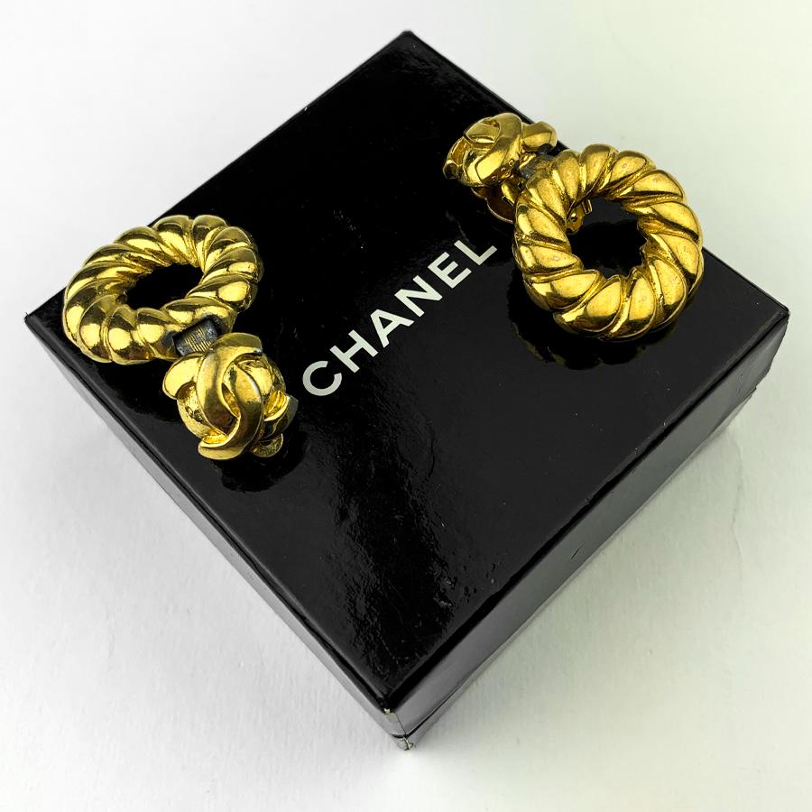 The earrings come from Maison CHANEL. They each represent a twisted round in golden metal which closes with a clip on which we find the CC logo of the brand.
The clips are vintage and in good condition. Only traces of metal oxidation are present