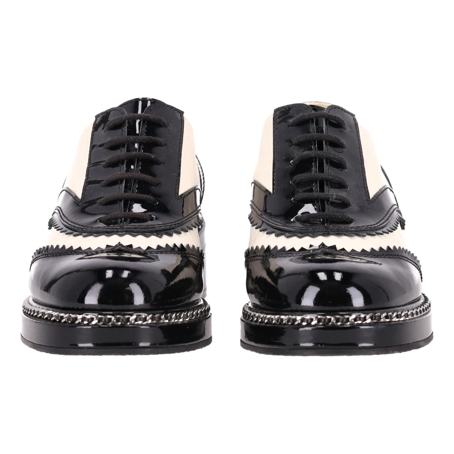 We Adore - Chanel Two-Tone Patent Leather Chain & Logo Detail Oxford Brogues

Two-tone brogues crafted from white leather and shiny black patent leather.

Adorned with Chanel's signature leather and chain detail trim.

Featuring 'CHANEL' signature