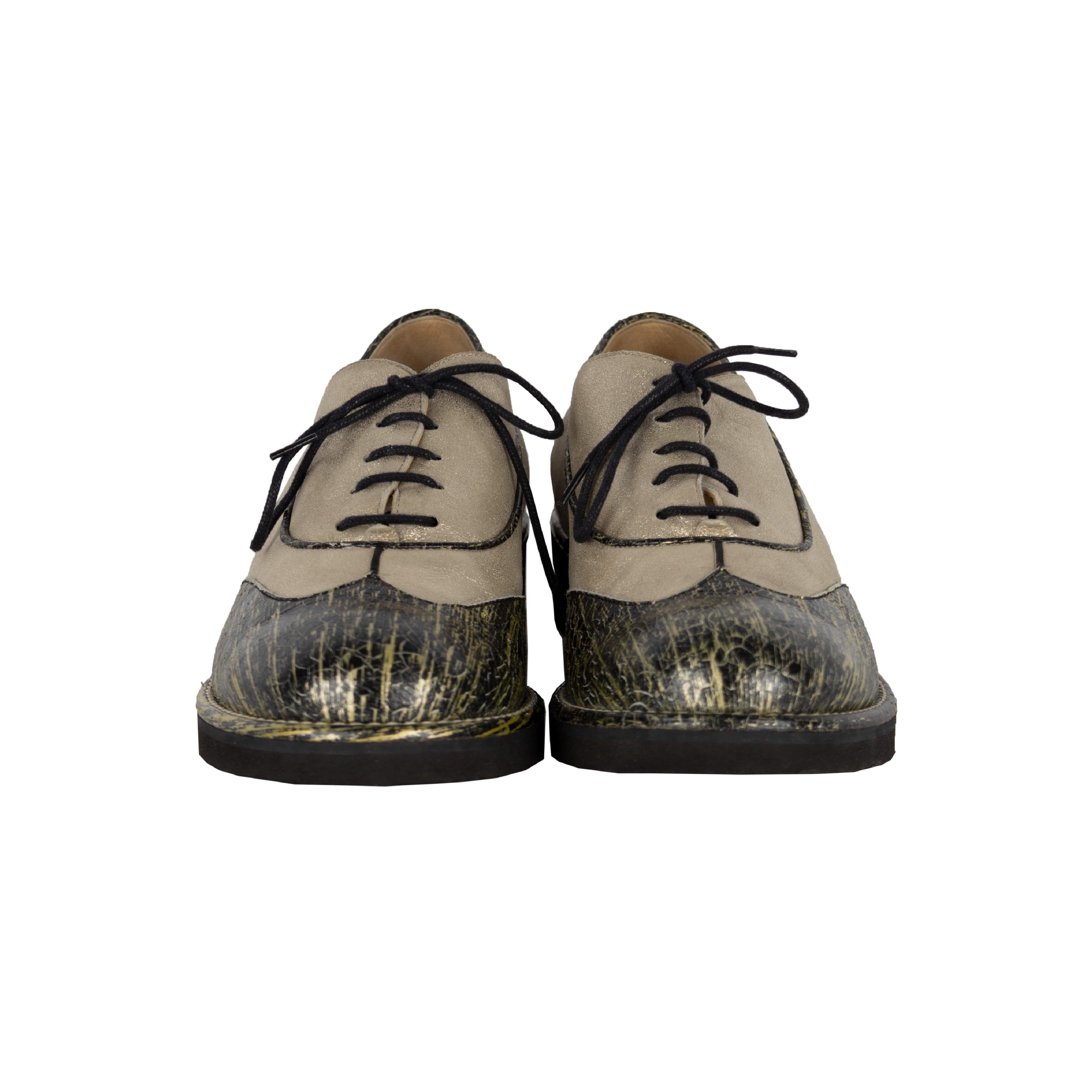 Ces chaussures d'Oxford intemporelles de Chanel sont faites d'un cuir or pâle chatoyant avec une finition vieillie pulvérisée noire et or dans un design contrasté bicolore et le logo CC embossé à l'arrière et sur la semelle. La fermeture à lacets et