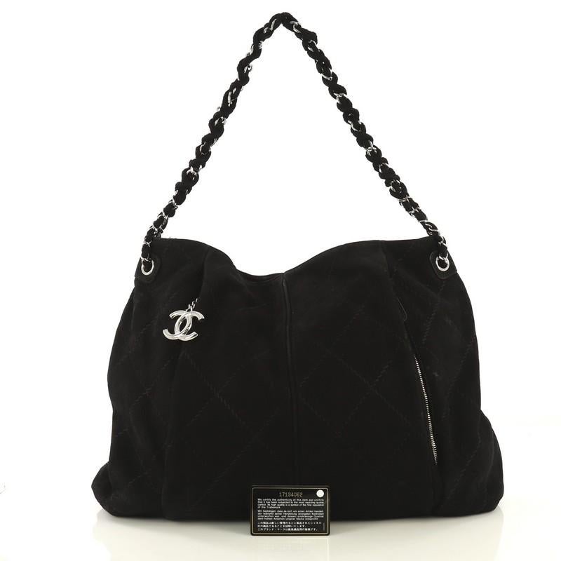 This Chanel Ultimate Stitch Hobo Quilted Nubuck Large, crafted from black quilted nubuck, features braided woven in leather chain link strap, two exterior zip pockets, and silver-tone hardware. It opens to a black fabric interior with zip and slip