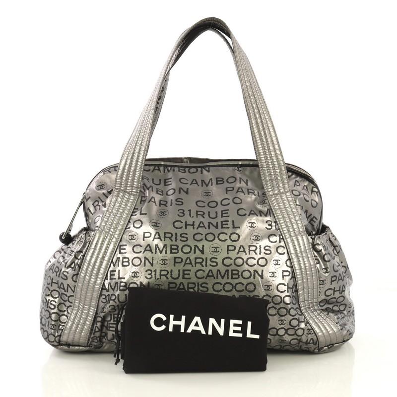 This Chanel Unlimited Bowling Bag Printed Nylon Large, crafted in metallic black and gray printed nylon, features dual-flat nylon strap, printed Chanel Paris 31 Rue Cambon all over, exterior side pockets and silver-tone hardware accents. Its zip