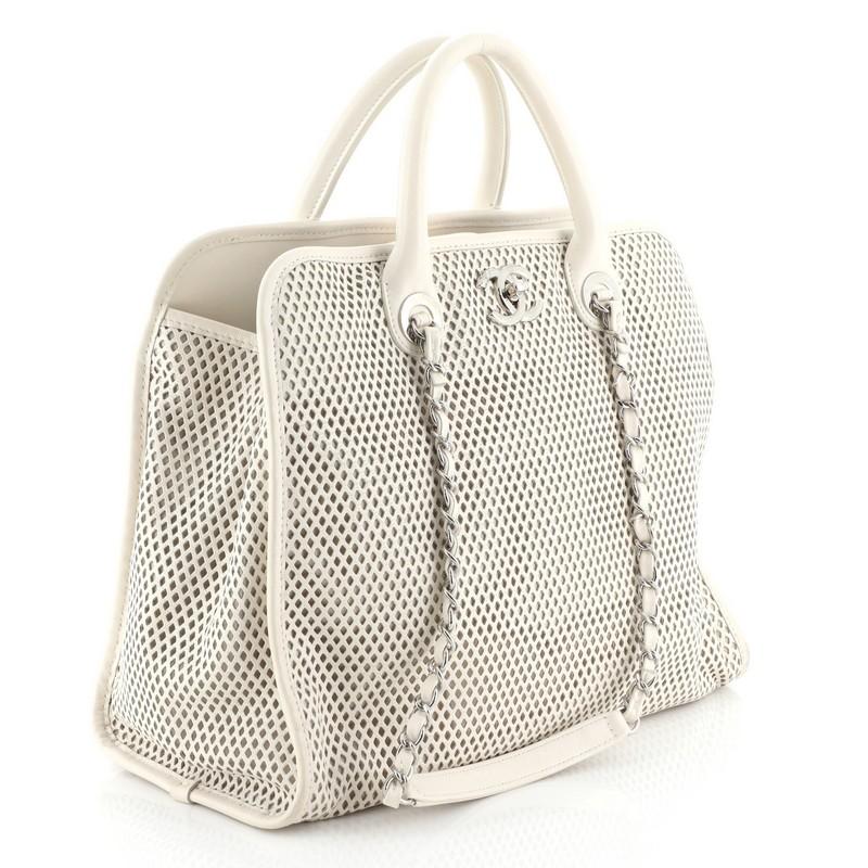This Chanel Up In The Air Convertible Tote Perforated Leather, crafted in neutral perforated leather, features dual woven-in leather chain straps with leather pads, dual-rolled leather handles, CC logo, and silver-tone hardware. Its magnetic snap