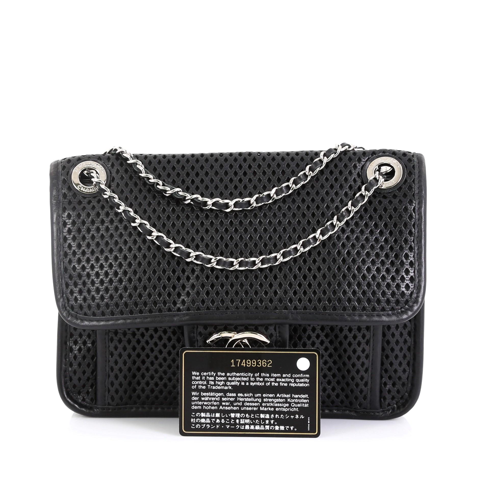 This Chanel Up In The Air Flap Bag Perforated Leather Small, crafted from black perforated leather, features woven-in leather chain strap, an extra front compartment under flap, and silver-tone hardware. Its turn-lock closure opens to a black fabric