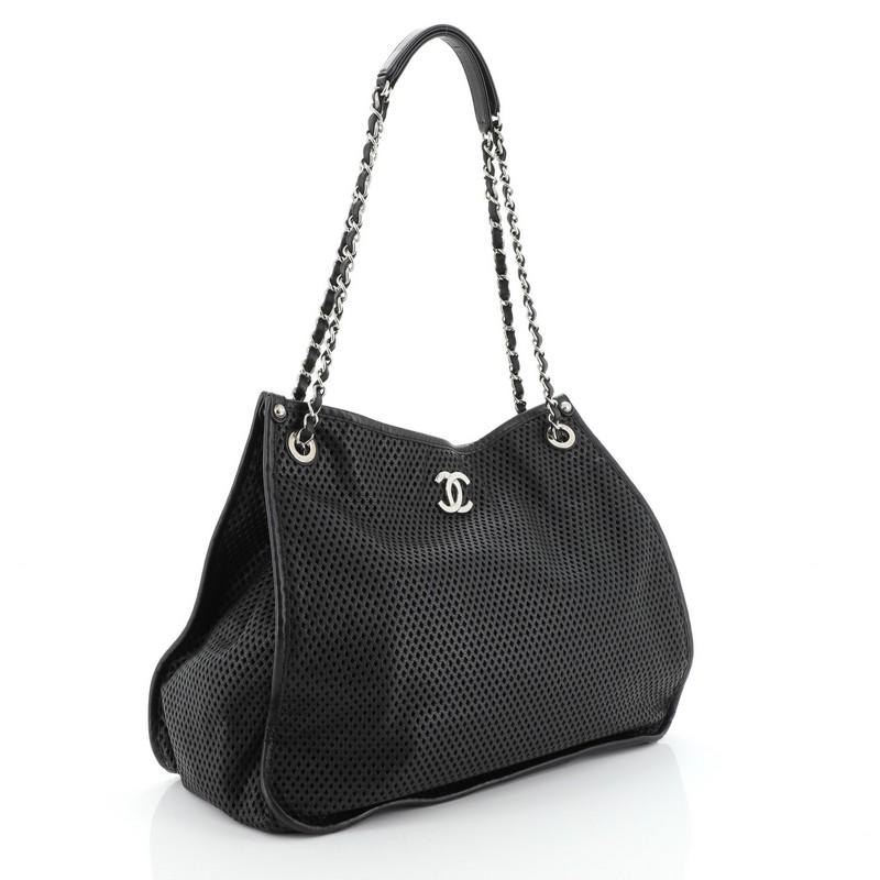 This Chanel Up In The Air Tote Perforated Leather, crafted in black diamond laser-cut leather, features woven in leather chain straps with leather pads, CC logo, protective base studs and silver-tone hardware. Its magnetic snap closure opens to a