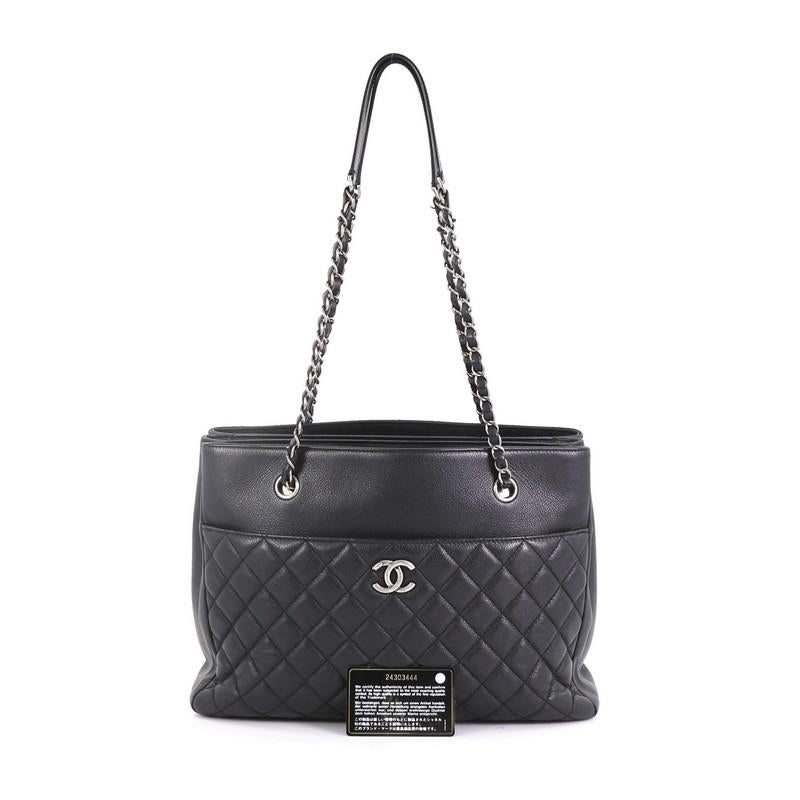This Chanel Urban Companion Shopping Tote Quilted Caviar Medium, crafted in black leather, features dual woven-in leather chain straps with leather pad, exterior back slip pocket and aged silver-tone hardware. Its magnetic closure opens to a black