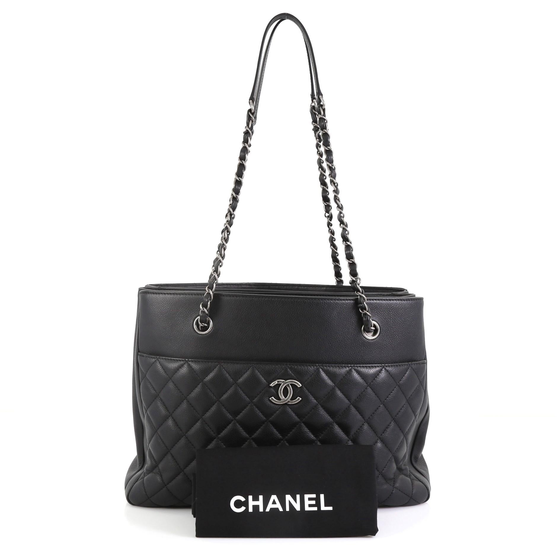 This Chanel Urban Companion Shopping Tote Quilted Caviar Medium, crafted in black leather, features dual woven-in leather chain straps with leather pad, exterior back slip pocket and aged silver-tone hardware. It opens to a black fabric interior