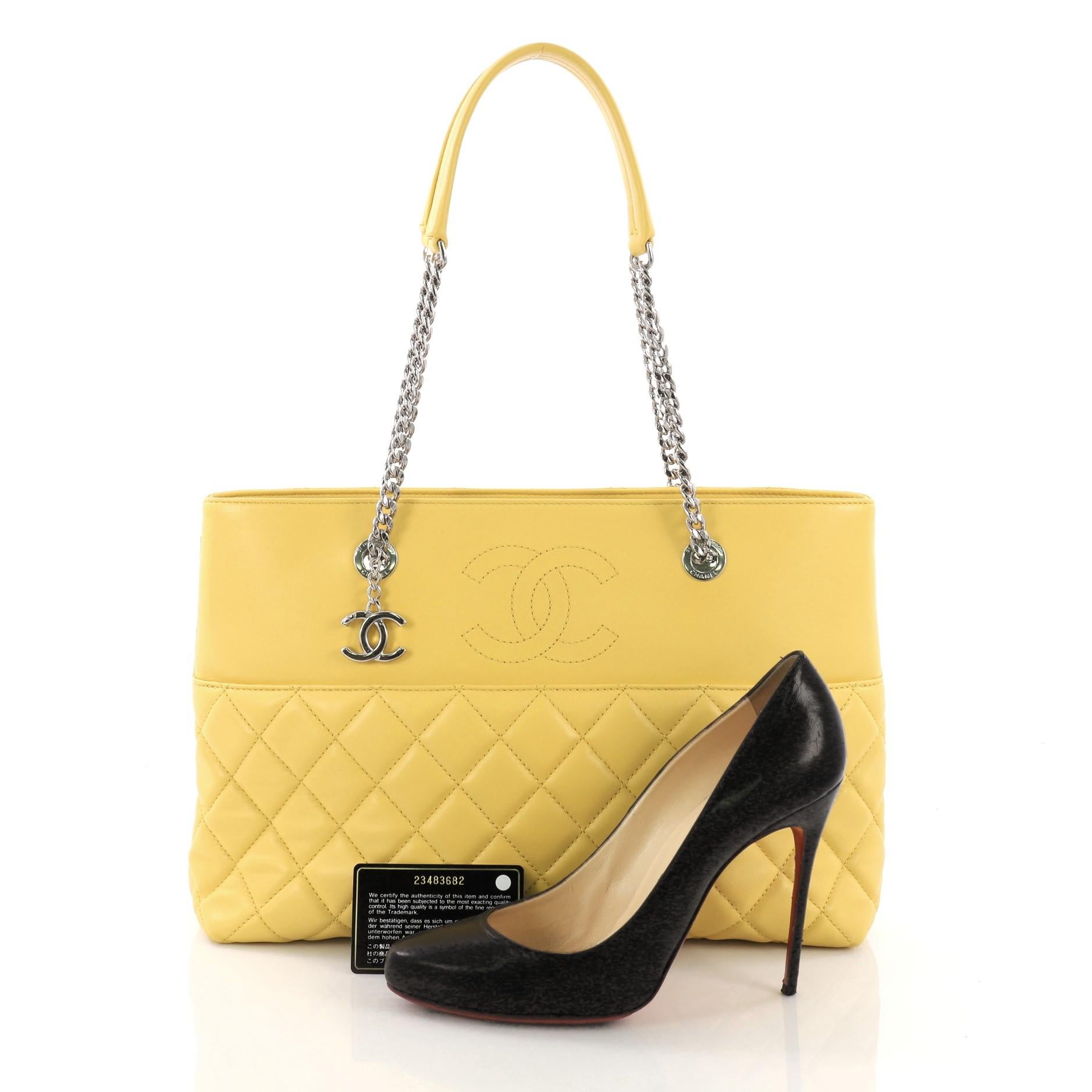 This Chanel Urban Delight Chain Tote Quilted Lambskin Large, crafted from yellow quilted lambskin, features dual chain link straps with leather pads, exterior slip pocket, and silver-tone hardware. Its magnetic snap button closure opens to a yellow