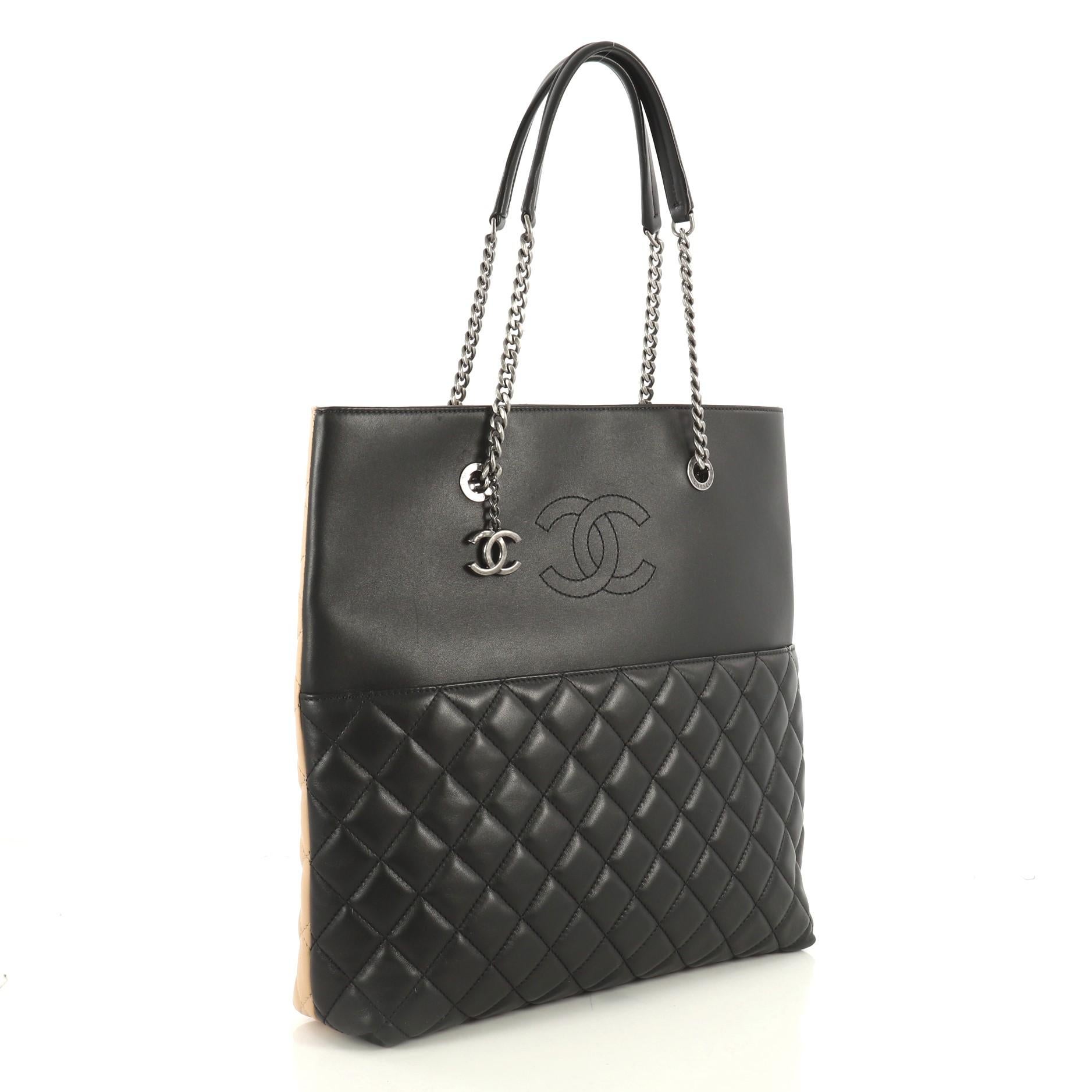 This Chanel Urban Delight Chain Tote Quilted Lambskin Large, crafted from black quilted lambskin leather, features dual chain link straps with leather pads, exterior slip pocket, and aged silver-tone hardware. Its magnetic snap button closure opens