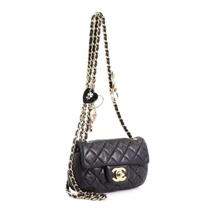 This Chanel Valentine Hearts Flap Bag Quilted Lambskin Extra Mini, crafted from black quilted leather, features woven-in leather chain link strap with valentine charms, and gold-tone hardware. Its CC turn-lock closure opens to a black fabric and