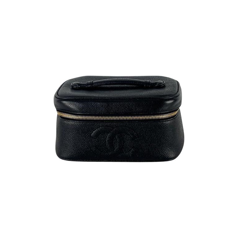 Magnifique Vanity Case de la Maison CHANEL, réalisé en cuir d'agneau noir et orné d'une bijouterie dorée. Véritable icône des années 1990, ce modèle a été conçu sous la direction de Karl Lagerfeld pour combiner élégance et fonctionnalité.

Son cuir