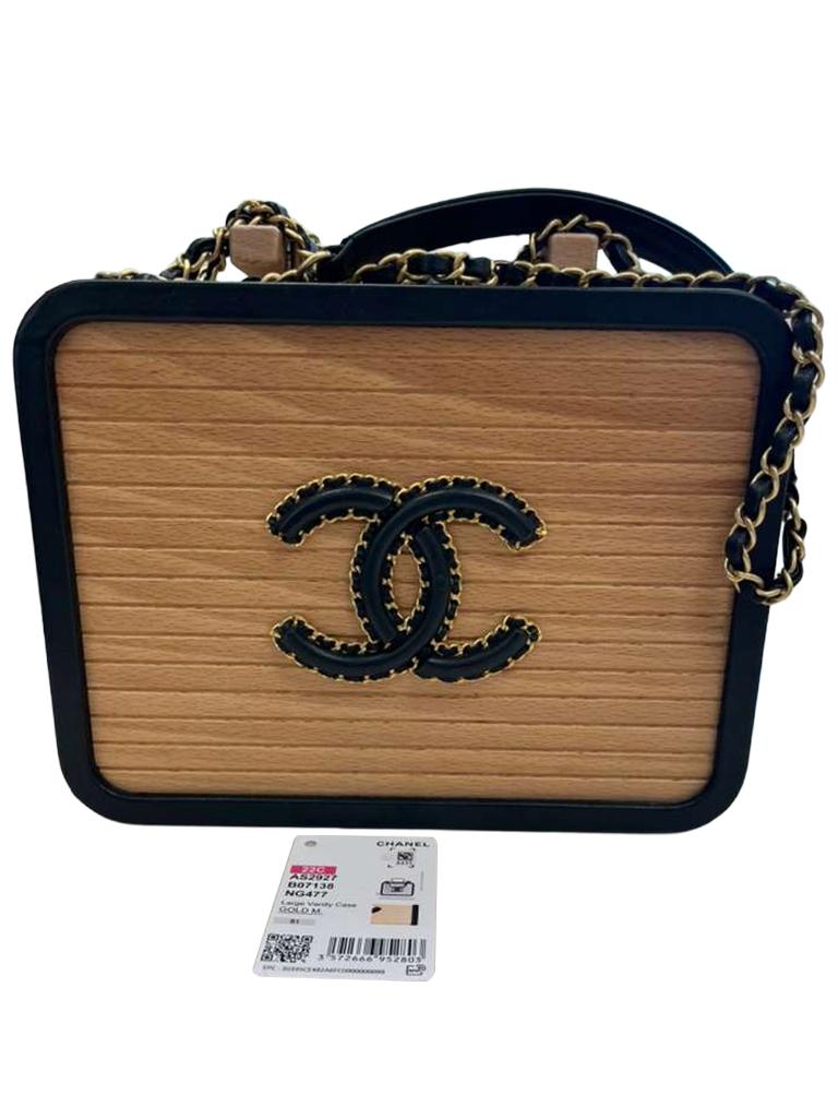 Ce vanity case est méticuleusement fabriqué à partir de bois de hêtre, de peau de vache et d'une chaîne en métal. Sa forme ronde est garnie de cuir de vache noir, mettant en valeur des détails exquis. Doté de la chaîne en cuir emblématique de CHANEL
