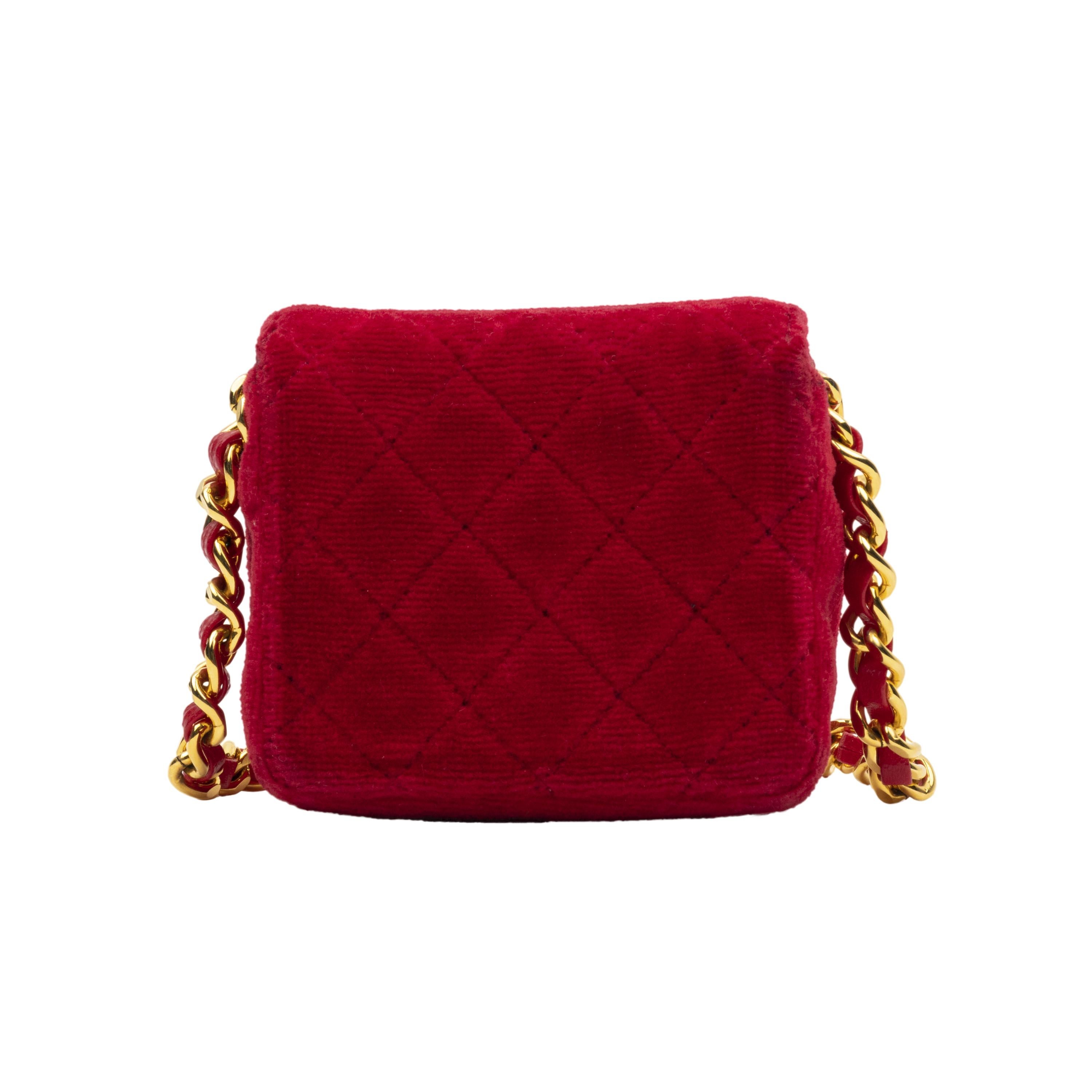 Chanel red velvet micro bag. This style is enhanced with diamond matelassé, golden details, pressure flap closure decorated with the crossed CC logo, and chain shoulder strap with intertwined with leather. The interior is black with the golden logo.