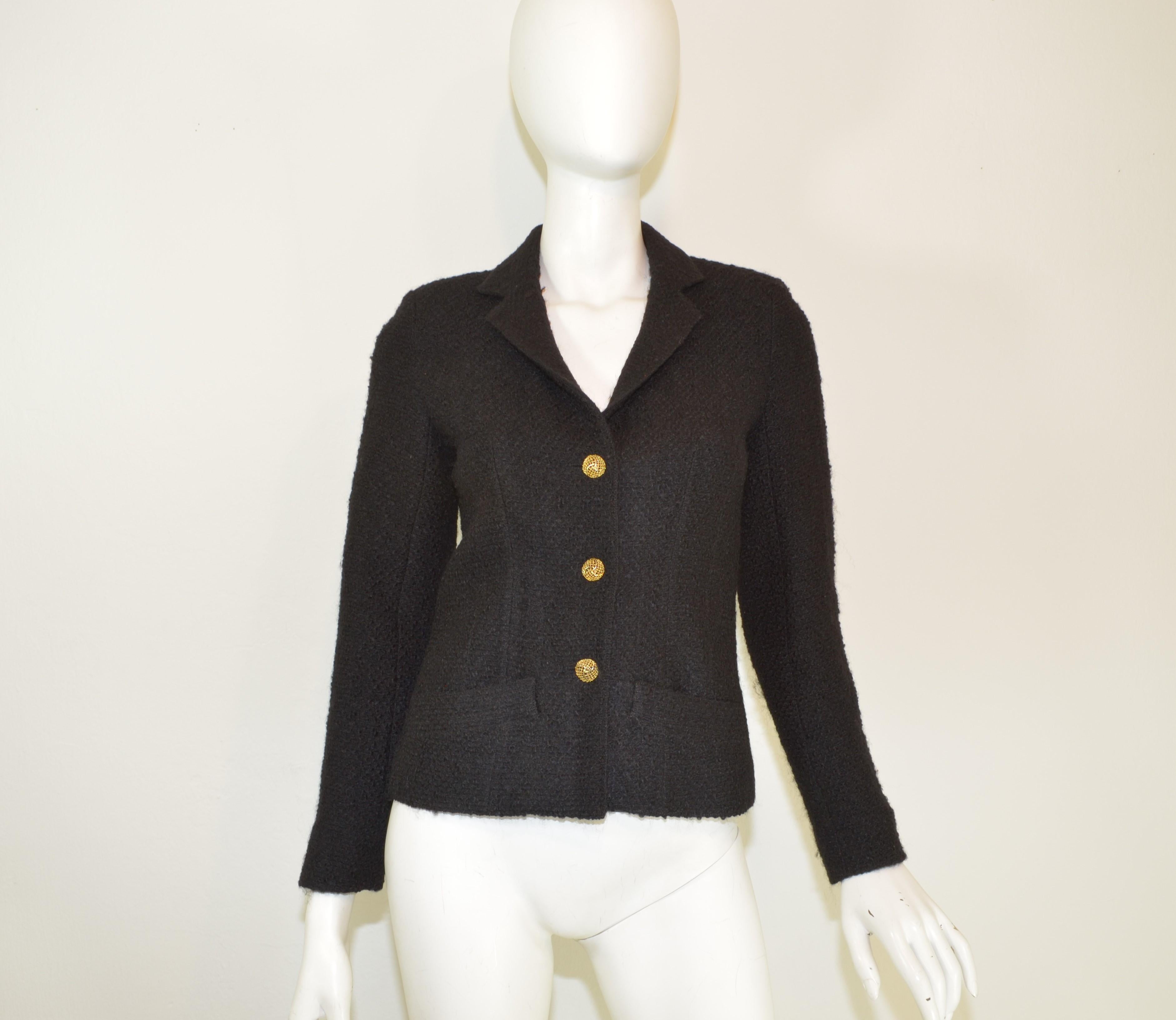 This classic, vintage Chanel (pre Karl Lagerfeld) jacket is featured in a black tweed knit with gold-tone button fastenings along the front and along the cuffs of the sleeves, pockets at the waist, and a full lining.

Excellent condition with no