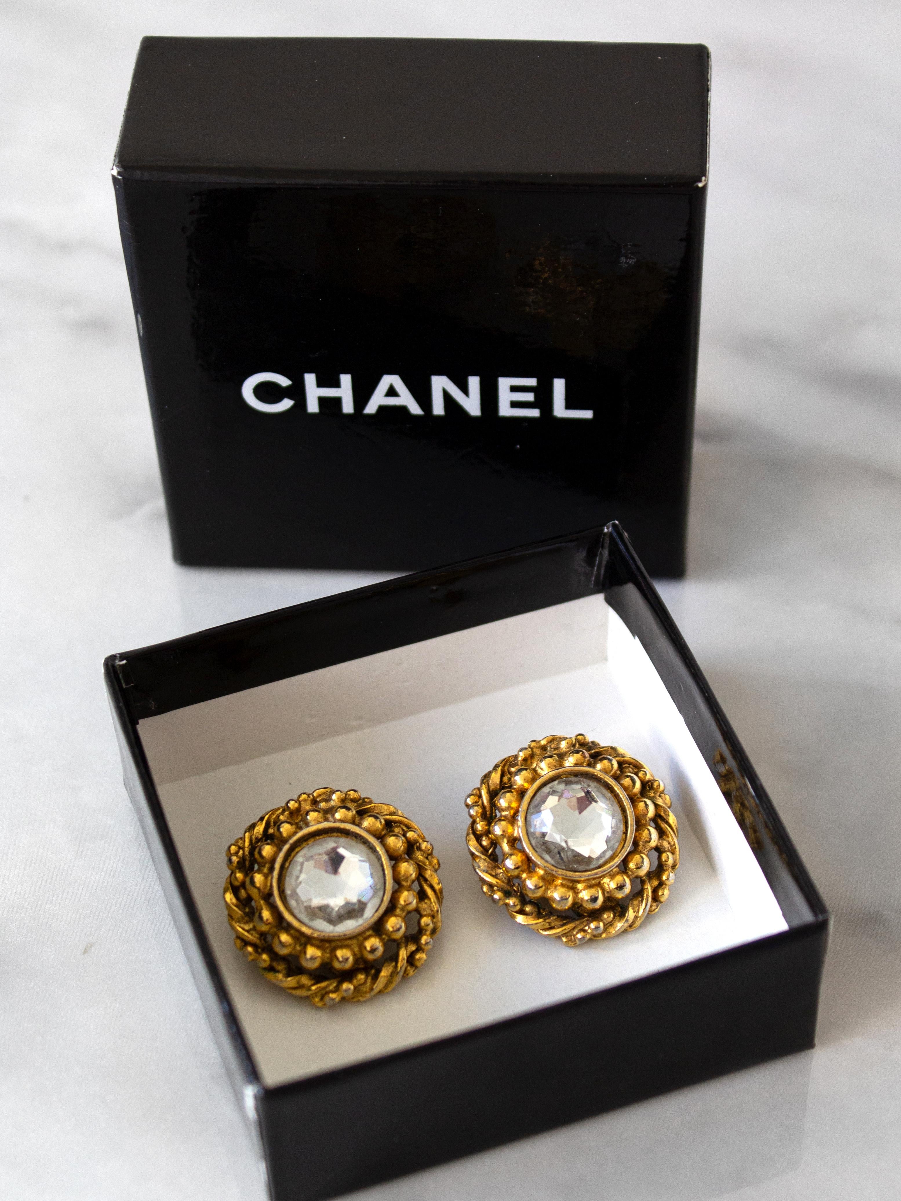 These vintage Chanel clip-on earrings from the 1970s are timeless and elegant. Each earring has a sparkling rhinestone center, surrounded by classic dots and a twisted rope design. The gold-plated setting adds a touch of sophistication, and the
