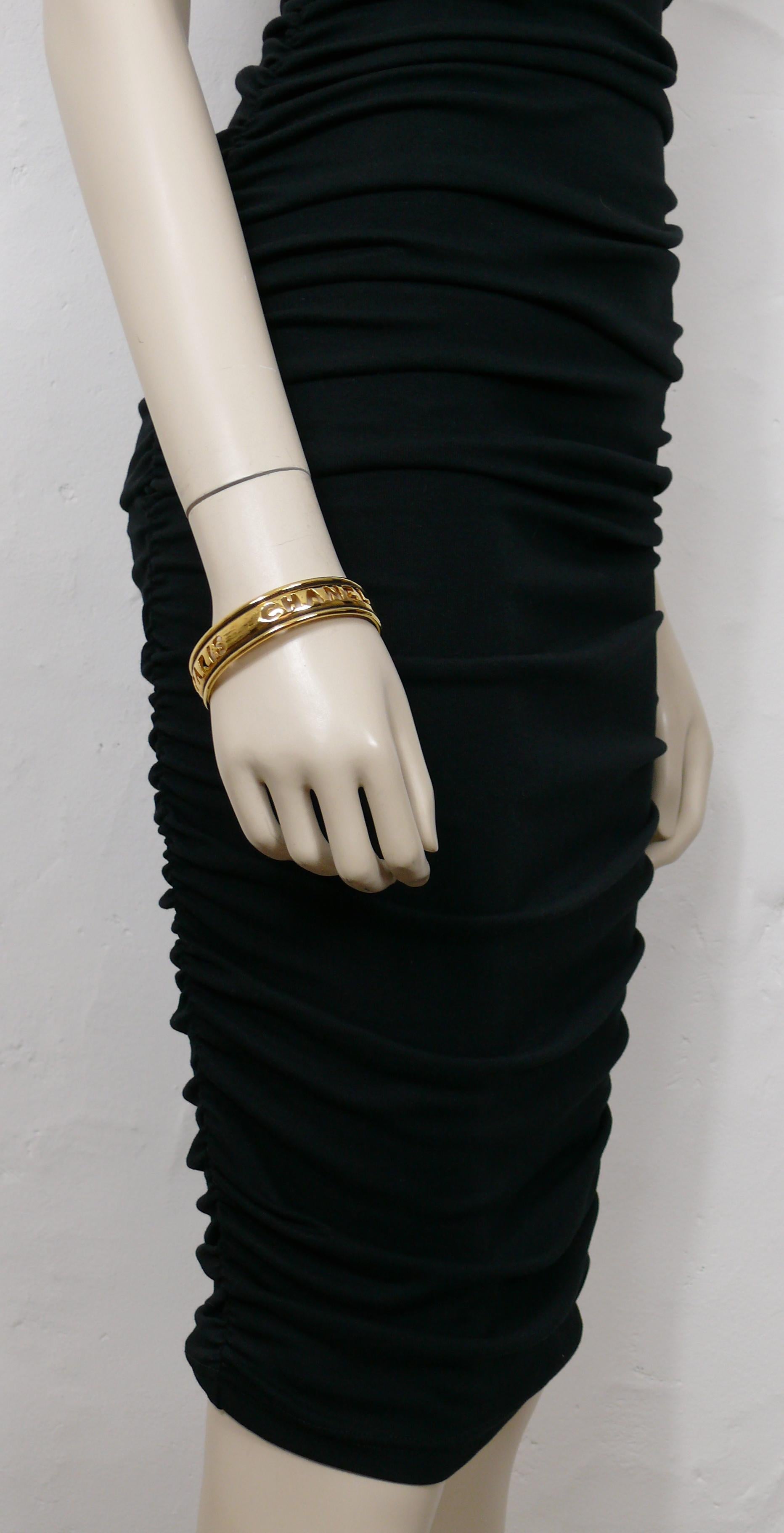 CHANEL vintage des années 1980, bracelet en or patiné avec des découpes CHANEL PARIS.

Non signé (habituel sur ce modèle).

Mesures indicatives : circonférence intérieure environ 21,99 cm (8,66 pouces) / largeur environ 1,6 cm (0,63 pouce).

Livré