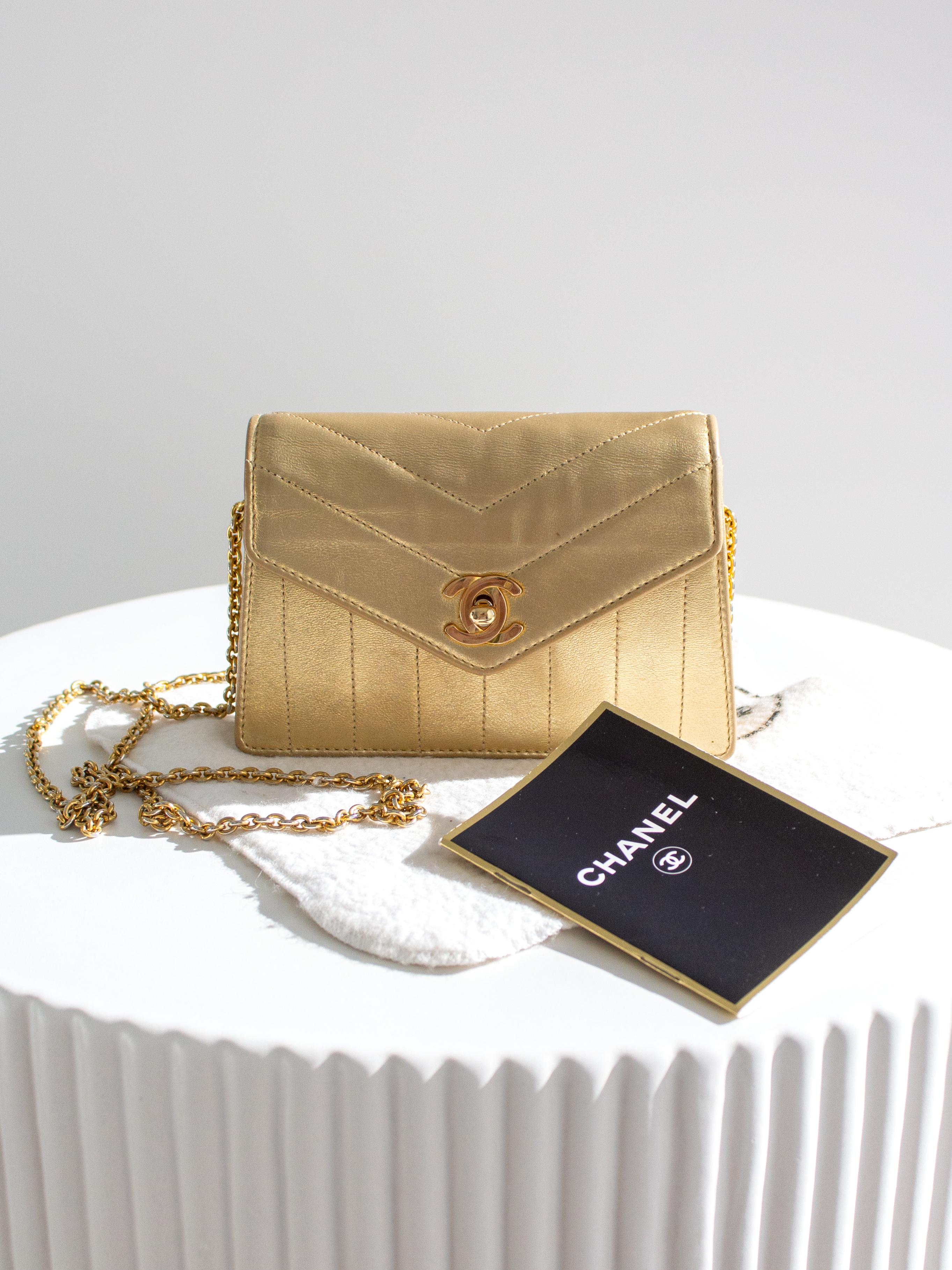 Ce mini sac trapézoïdal vintage Chanel des années 1980 est une pièce éblouissante réalisée en cuir d'agneau luxueux dans une teinte or métallisé saisissante. Il est doté d'un cadenas CC plaqué or 24 carats avec un poinçon, d'une longue chaîne et