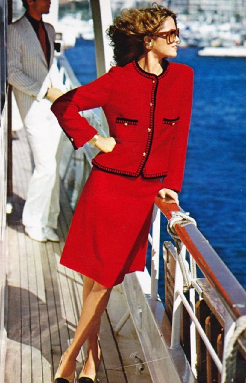 Entrez dans l'élégance intemporelle avec ce tailleur en tweed iconique de Chanel datant de 1981. Confectionné dans la teinte rouge parisienne par excellence, il respire la sophistication grâce à ses bordures tressées contrastantes et à ses boutons