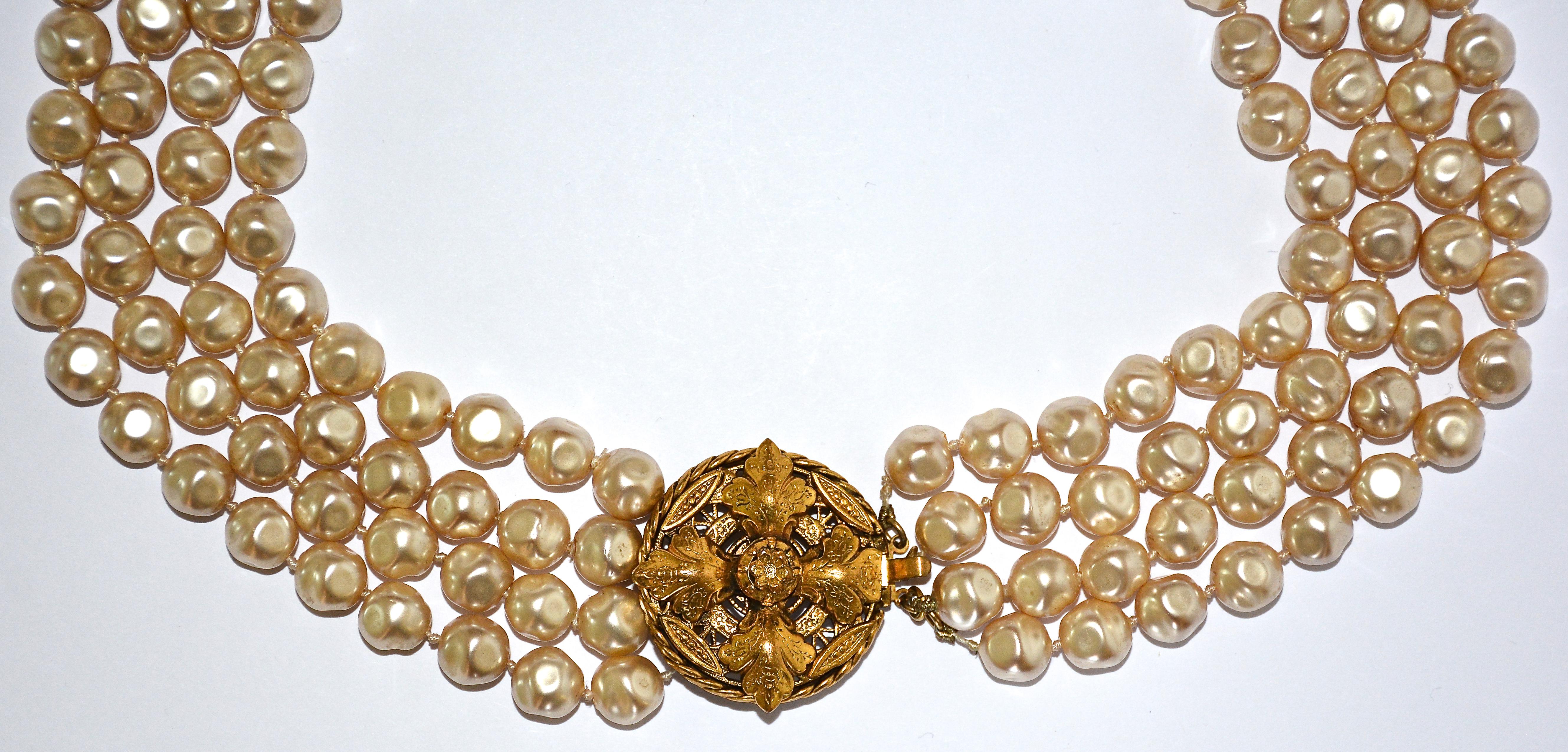 A gorgeous Chanel faux pearl necklace from the ultra-glamorous 1980s. 

This beauty of a necklace boasts four graduated strands of baroque pearls embellished with an ornately detailed gold medallion clasp. Stamped 'CHANEL, 1983' on the back of