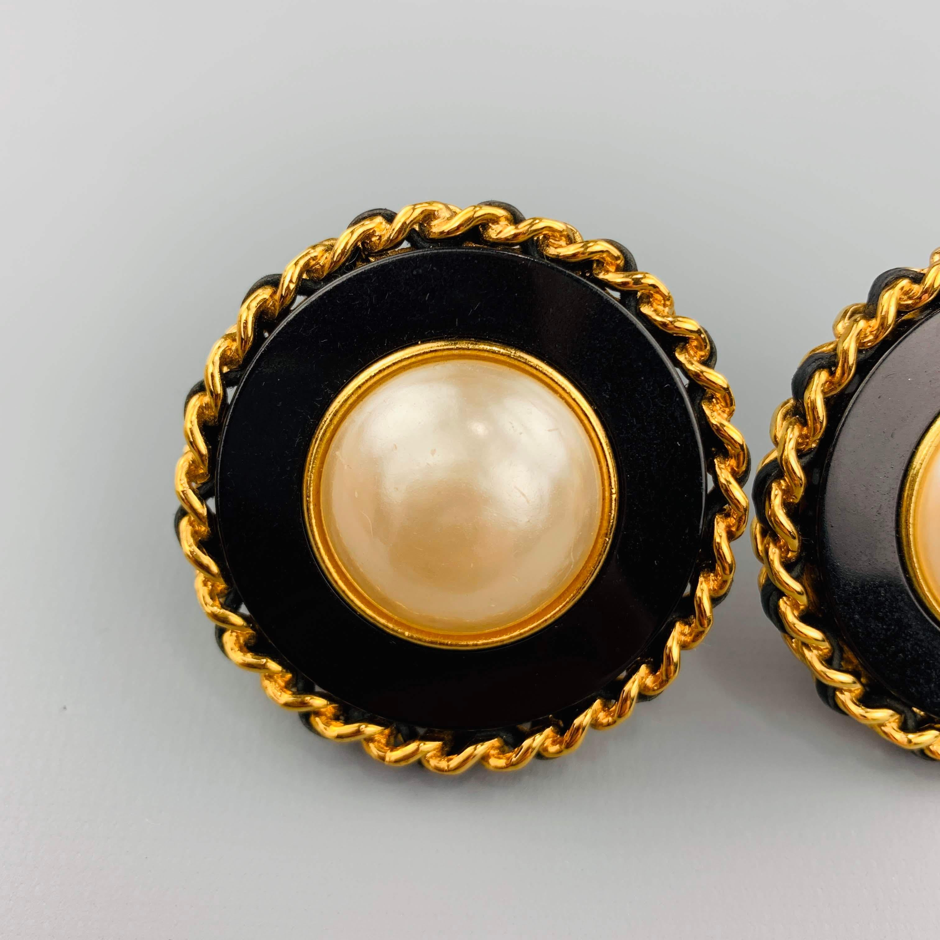 Vintage CHANEL (Circa 1986-1992) Season 28 clip on earrings feature a black enamel round base with a faux pearl center and yellow gold tone metal leather woven chain boarder. Made in France.
 
Very Good Pre-Owned Condition.
Marked: 28
 
5 cm.