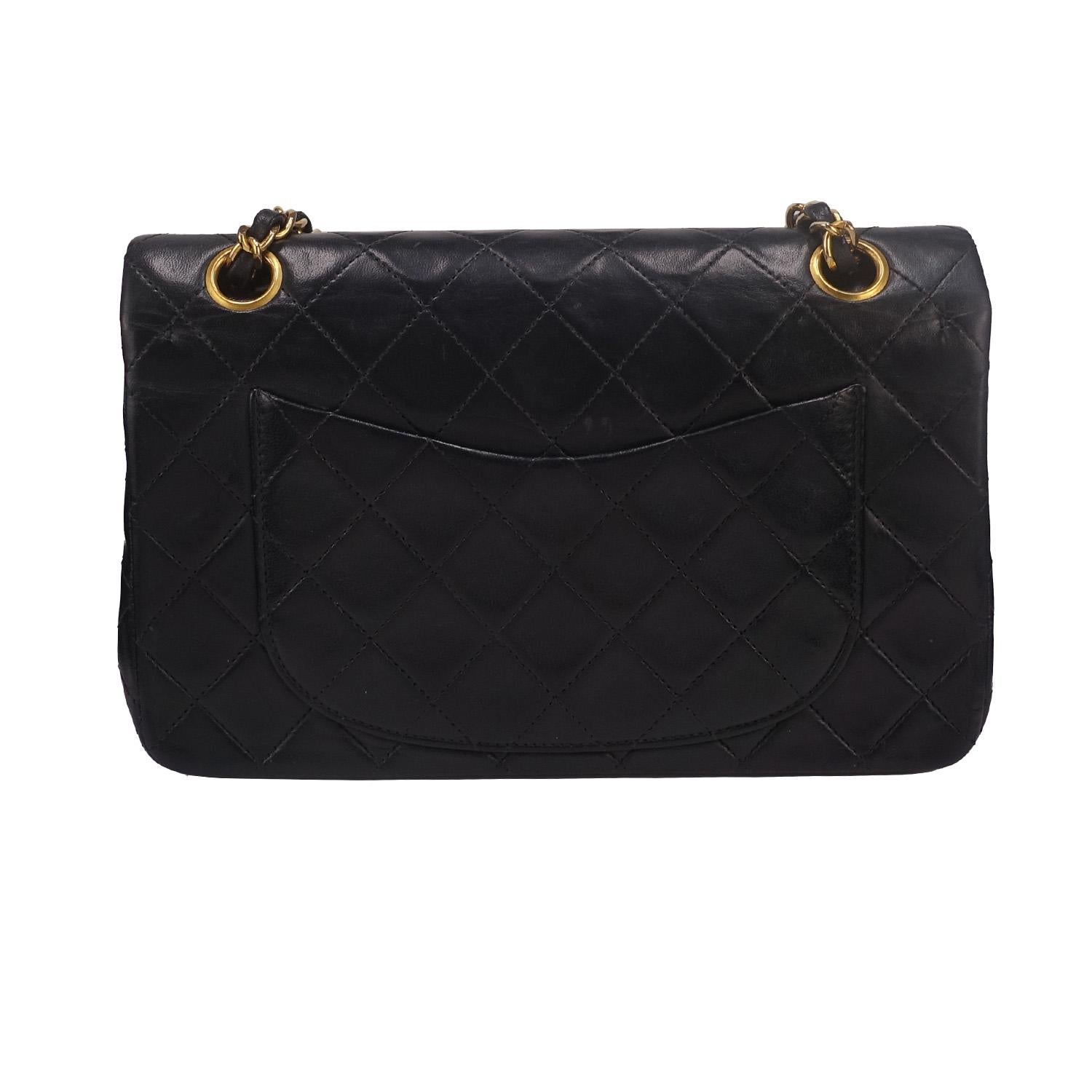 Plongez dans l'élégance intemporelle de ce sac à rabat classique de Chanel, issu des collections 1989 - 1991. Confectionné en cuir noir luxueux et orné des détails matelassés emblématiques, ce petit sac de 23 cm témoigne du style et du savoir-faire