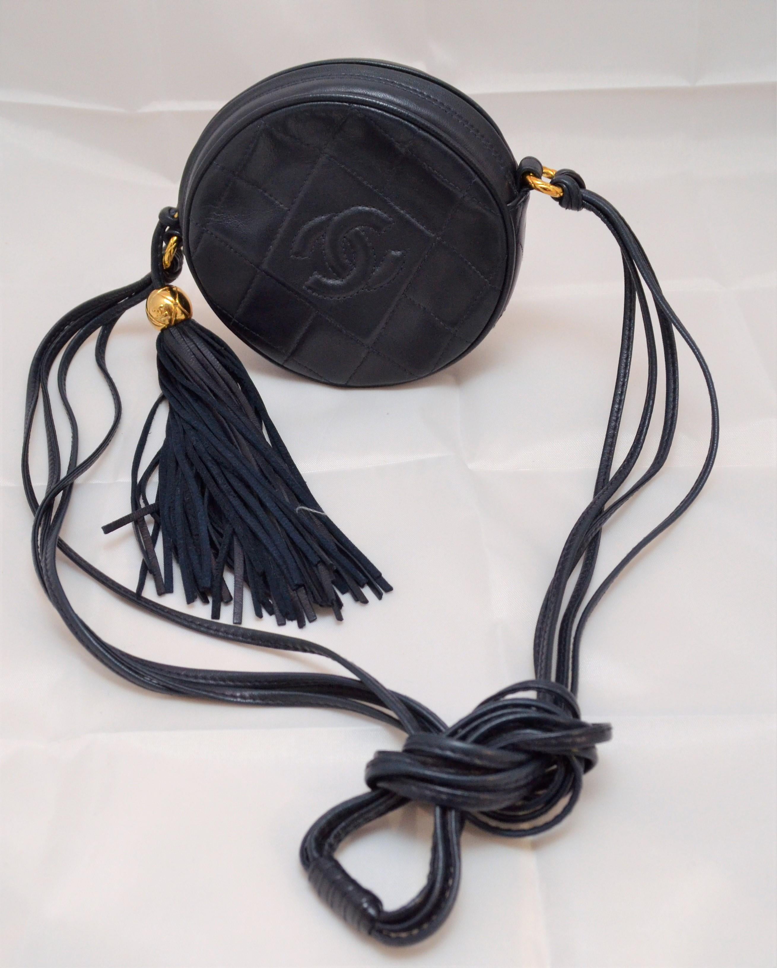 Chanel Vintage 1990's Navy Leather Circle Crossbody Bag --- Featured in navy quilted leather with an embossed signature CC at the front, zippered closure with a leather tassel zipper pull, interior fully lined in leather, made in Italy. Bag is in