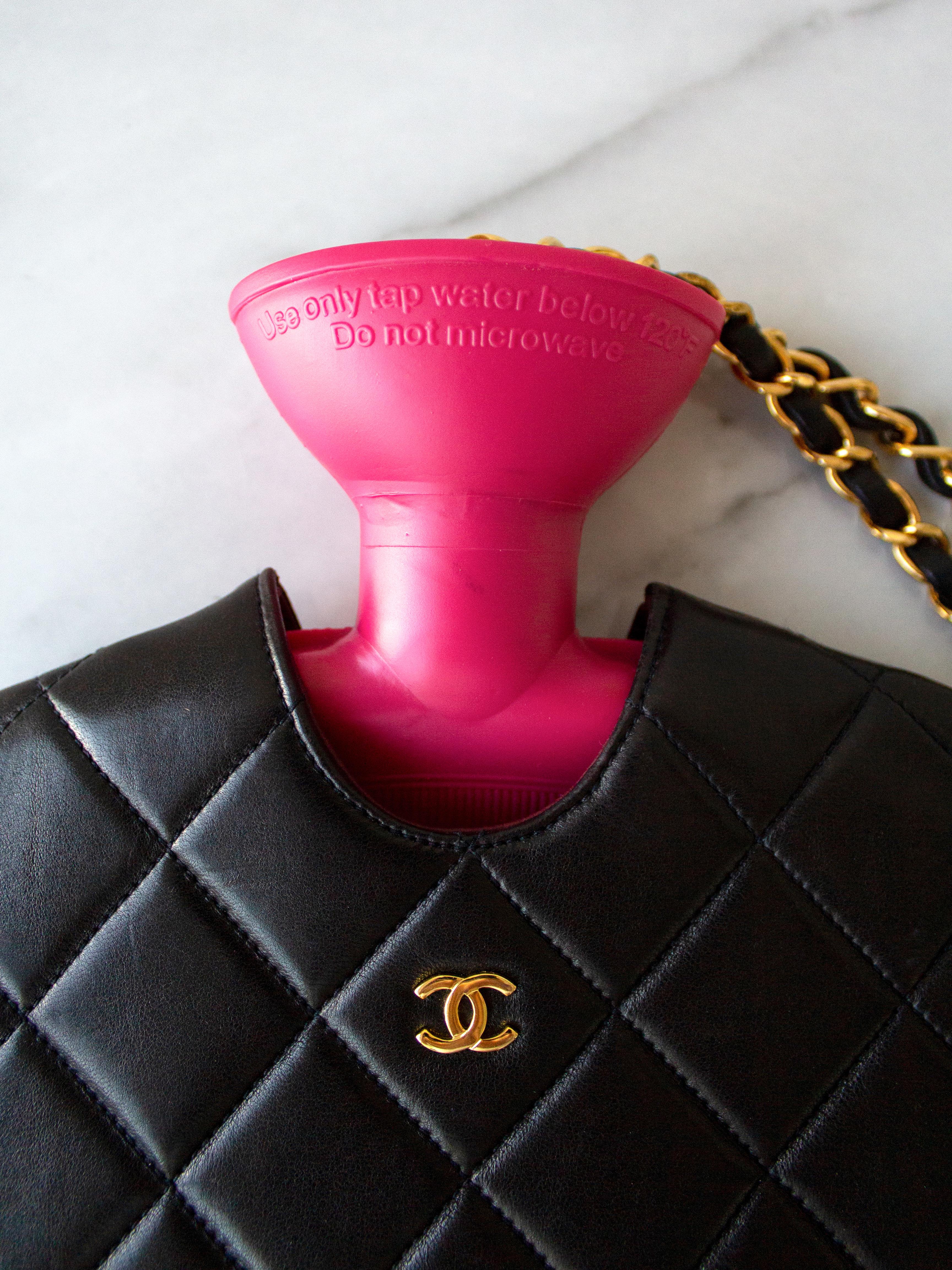 Extremely rare hot water bottle bag from Chanel Fall 1993 collection. A real gem for true collectors! Black quilted lambskin cover, in the shape of a miniature garment bag with zipper down the center that opens to reveal a pink rubber water bottle,