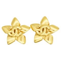 Boucles d'oreilles Chanel vintage de 1996 : modèle rare et emblématique avec logo « Blossom » représentant une étoile dorée et un pentagramme, motif CC