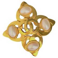 Spilla Chanel Vintage del 1997: grande croce dorata, perla bianca ovale, CC Coco traforata