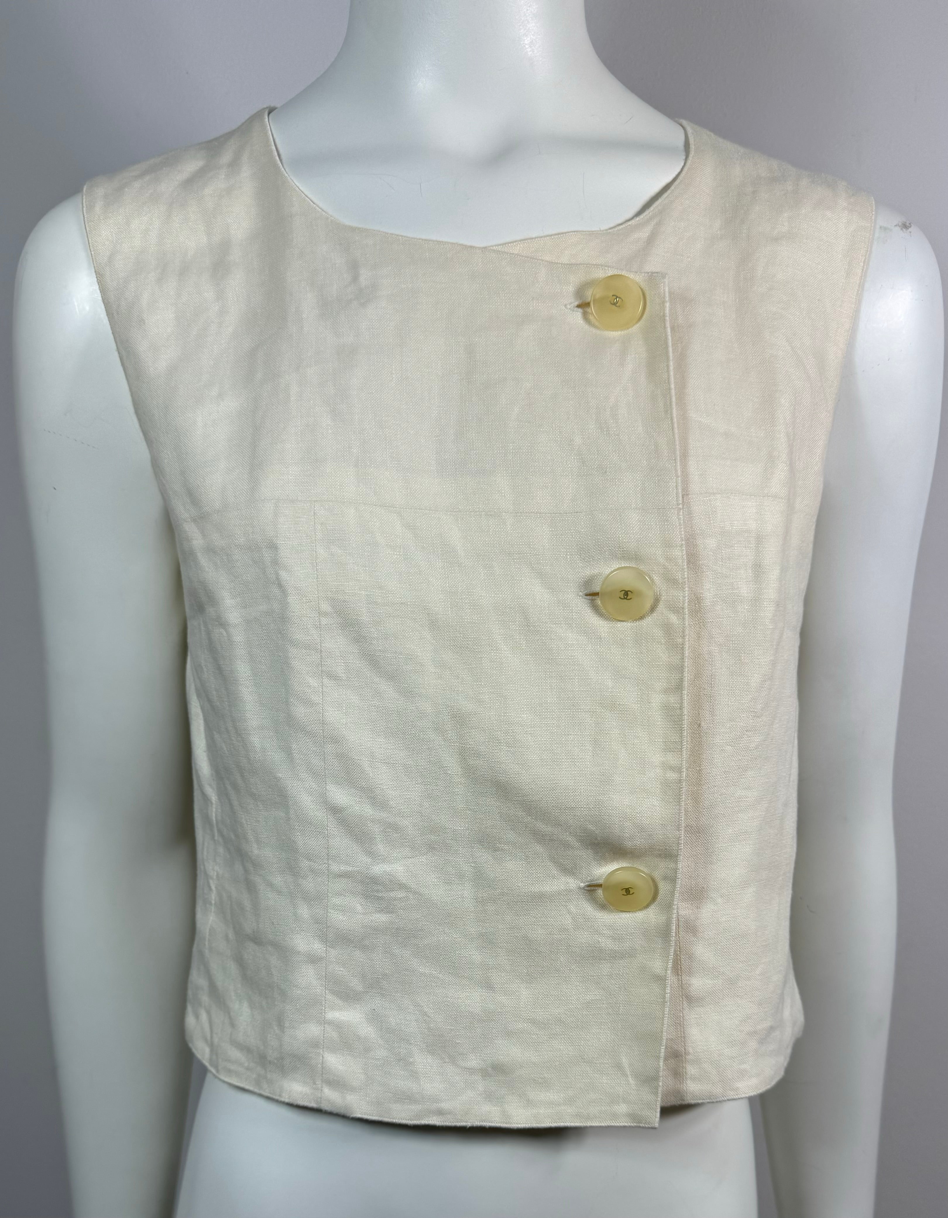 Haut court Chanel Vintage 2000 Cruise ivoire en lin - Taille 40  Ce haut sans manches en lin ivoire vintage est à double boutonnage bien que l'on ne voit qu'une seule rangée de 3 boutons opaques ivoire avec le cc doré au centre. Le haut a une