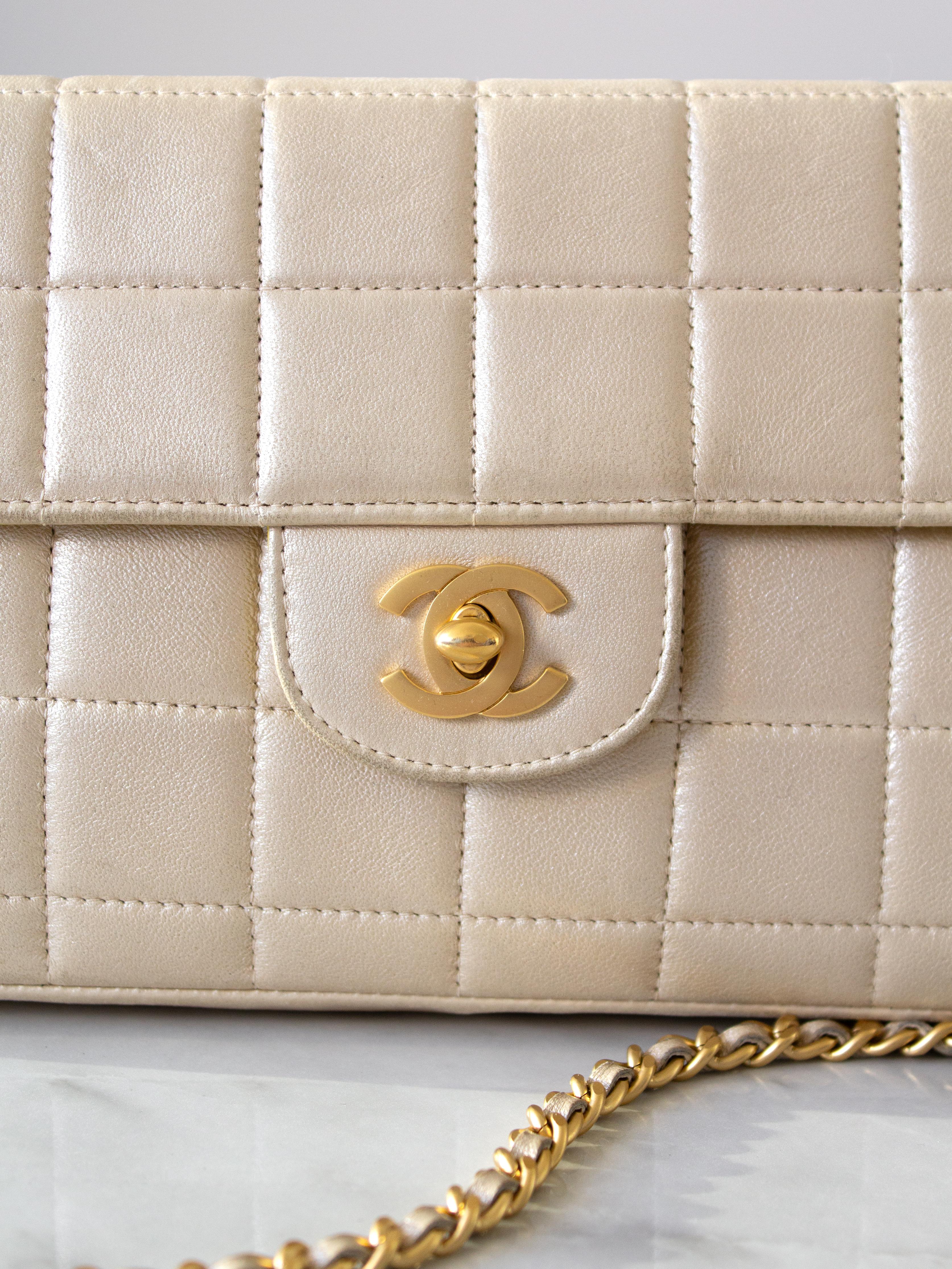 Die kultige Chanel East West Tasche aus dem Jahr 2002 bringt die Jahrtausendwende in Schwung. Dieses Schmuckstück zeigt sich in einer trendigen Baguette-Silhouette und der charakteristischen Chocolate Bar-Steppung. Die Tasche aus perlmuttgoldenem