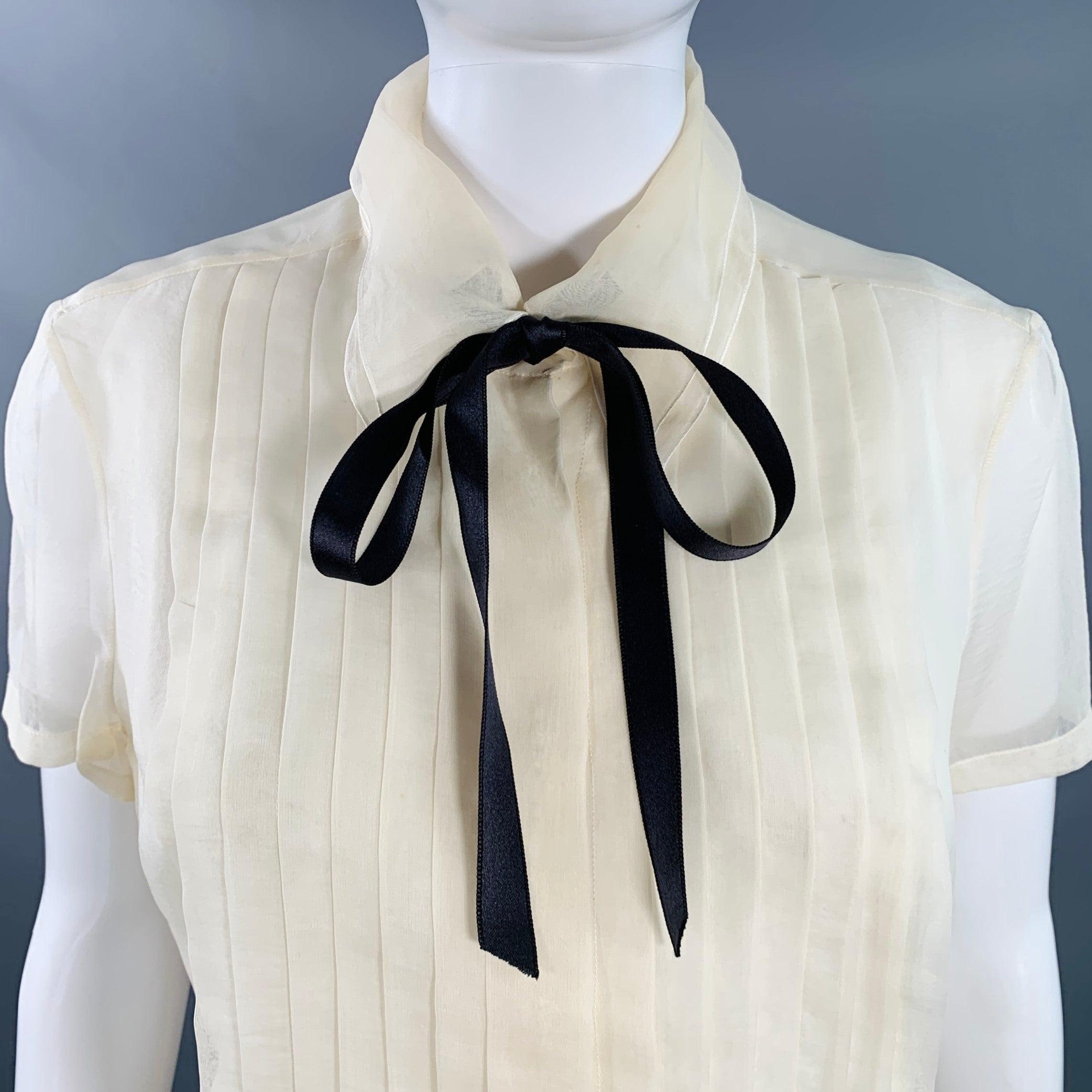 Vintage CHANEL 2003 Cruise Bluse
aus cremefarbener Seide mit doppellagigem Kragen, plissierter Vorderseite und verdeckter Knopfleiste mit schwarzer Fliege am Hals. Made in France. guter gebrauchter Zustand. Mehrere kleine Flecken, wie es ist.