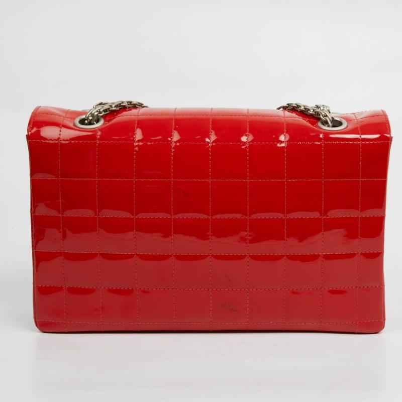 CHANEL 2.55 bag in red patent leather. The attributes are matt silver metal. The inside of the flap is in red leather while the storage space is in the same color fabric with a large zipped pocket. It can be worn on the shoulder or crossed. Apart