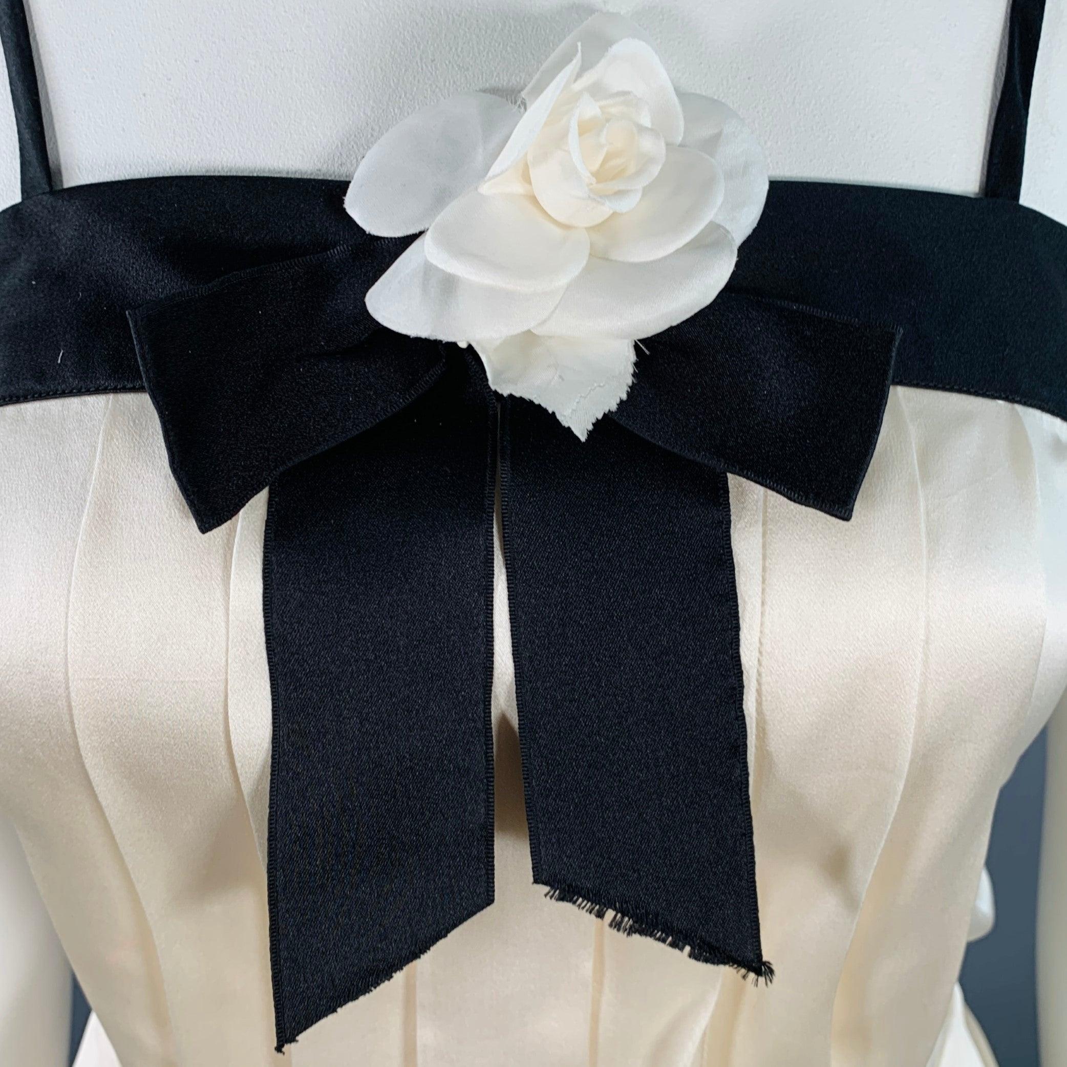 Vintage CHANEL BOUTIQUE 1990s dress top
in a cream and black silk featuring a camisole style, pleated front, black bow with signature camellia brooch, and back hidden buttons & snaps closure. Made in France.Very Good Pre-Owned Condition. Minor mark