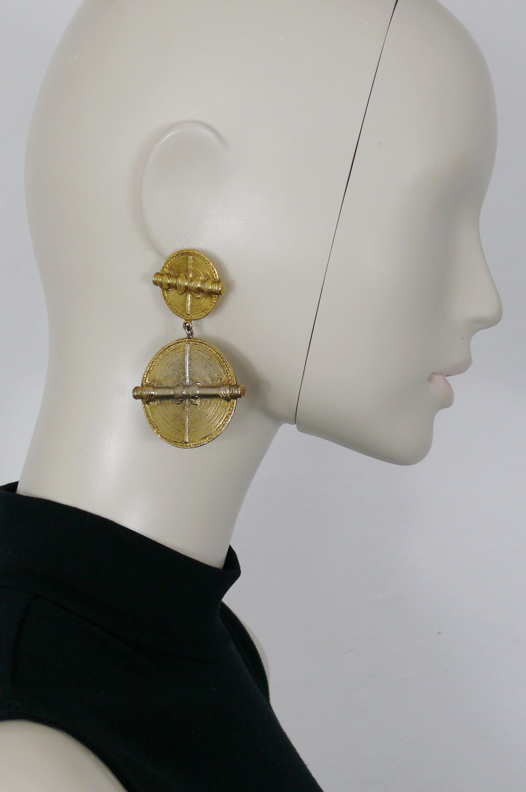 CHANEL vintage antiqued gold toned african inspired dangling earrings (clip-on) featuring two shields with concentric circle design. 

Embossed CHANEL.

Indicative measurements : height approx. 7.5 cm (2.95 inches) / max. width approx. 4.6 cm (1.81