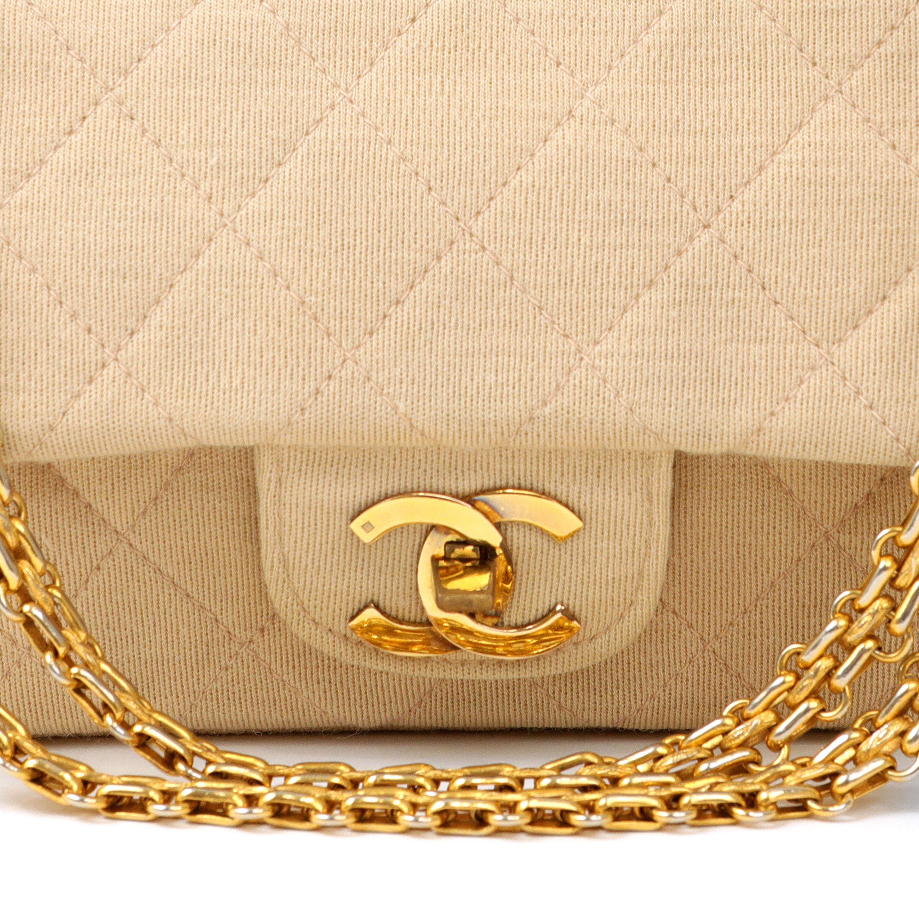 This authentic Chanel Beige Jersey Medium Classic Flap Bag is in excellent vintage condition.  Light tan jersey fabric is quilted in signature Chanel diamond pattern.  Gold tone interlocking CC twist lock clasp and bijoux style chain.   Dust bag