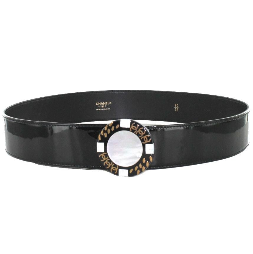 CHANEL belt in black patent leather and buckle in white mother-of-pearl.
Fall-Winter 1997 collection. The round shape buckle is in black and white mother-of-pearl with golden details representing a chain and the initials CC. Three notches for