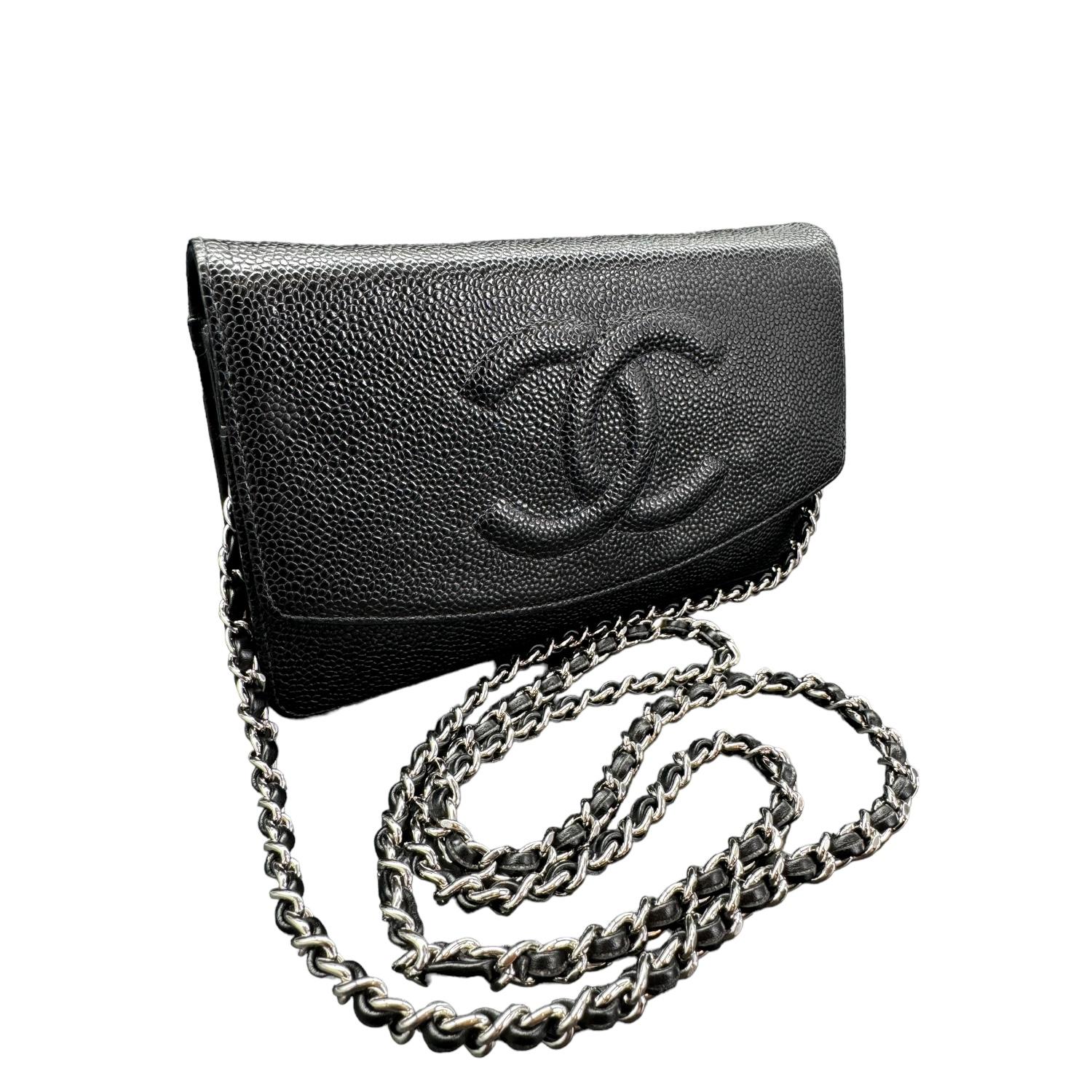 This stylish wallet is crafted of luxuriously textured caviar leather in black, with a Chanel CC logo embossed on the front. The bag features a leather threaded silver chain-link shoulder strap and a crossover flap. This opens to a black grosgrain