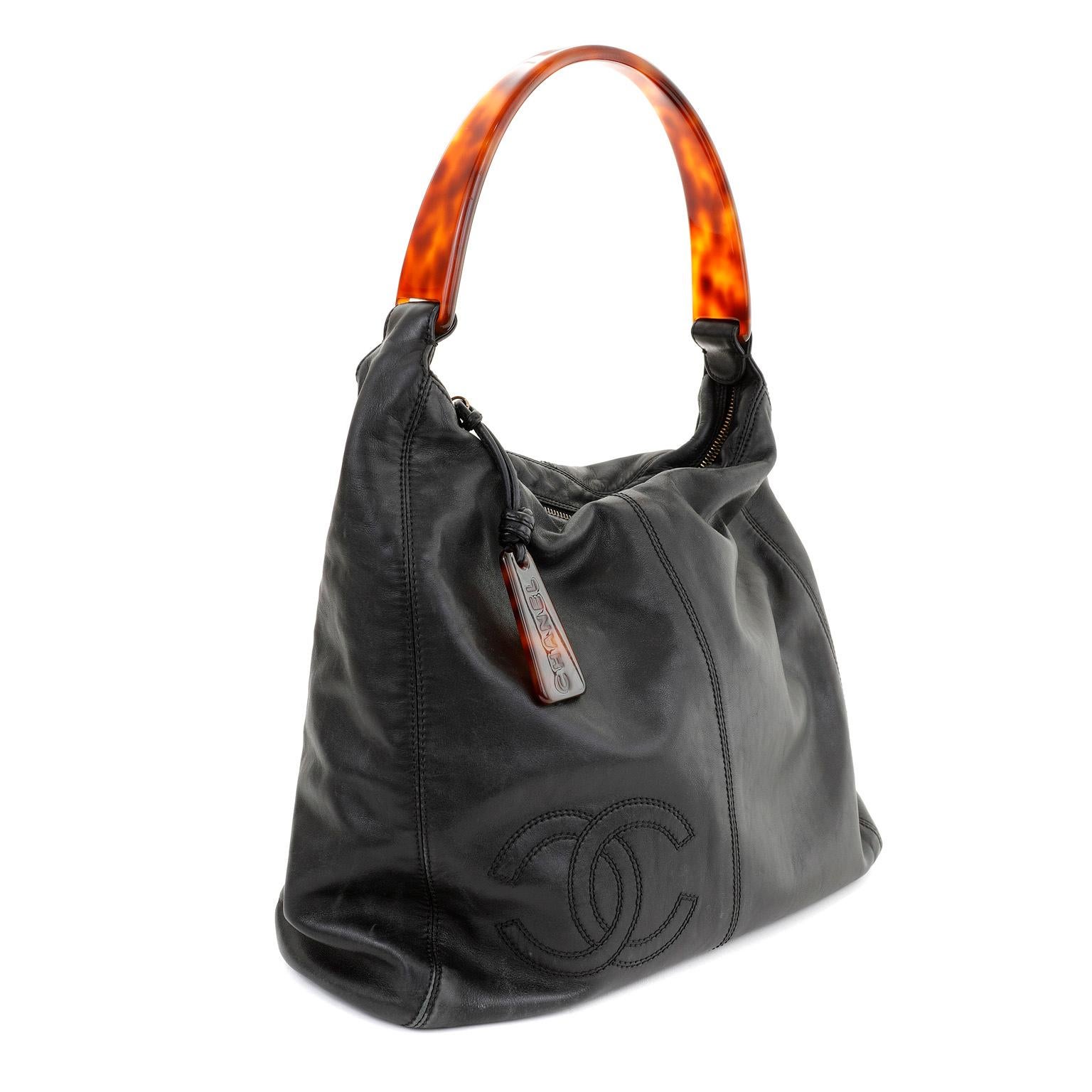 This authentic Chanel Black Lambskin CC Tortoise Handle Hobo is in excellent vintage condition.  Luxe black lambskin hobo with interlocking CC tonally stitched off center.  Secure zippered top closure with tortoise CHANEL engraved pull.  Single