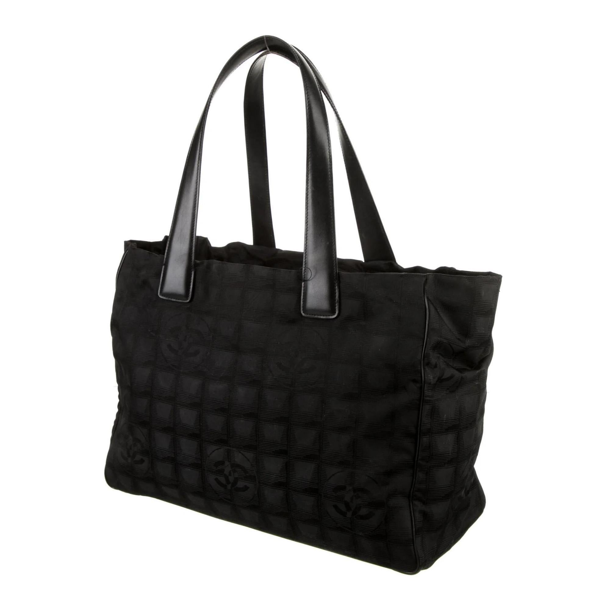 
This Chanel tote bag is made with black nylon with quilted squares and logo embellishment throughout. The bag features black leather trim, dual flat leather top handles, gold tone hardware, protective feet at base, an open top and black fabric