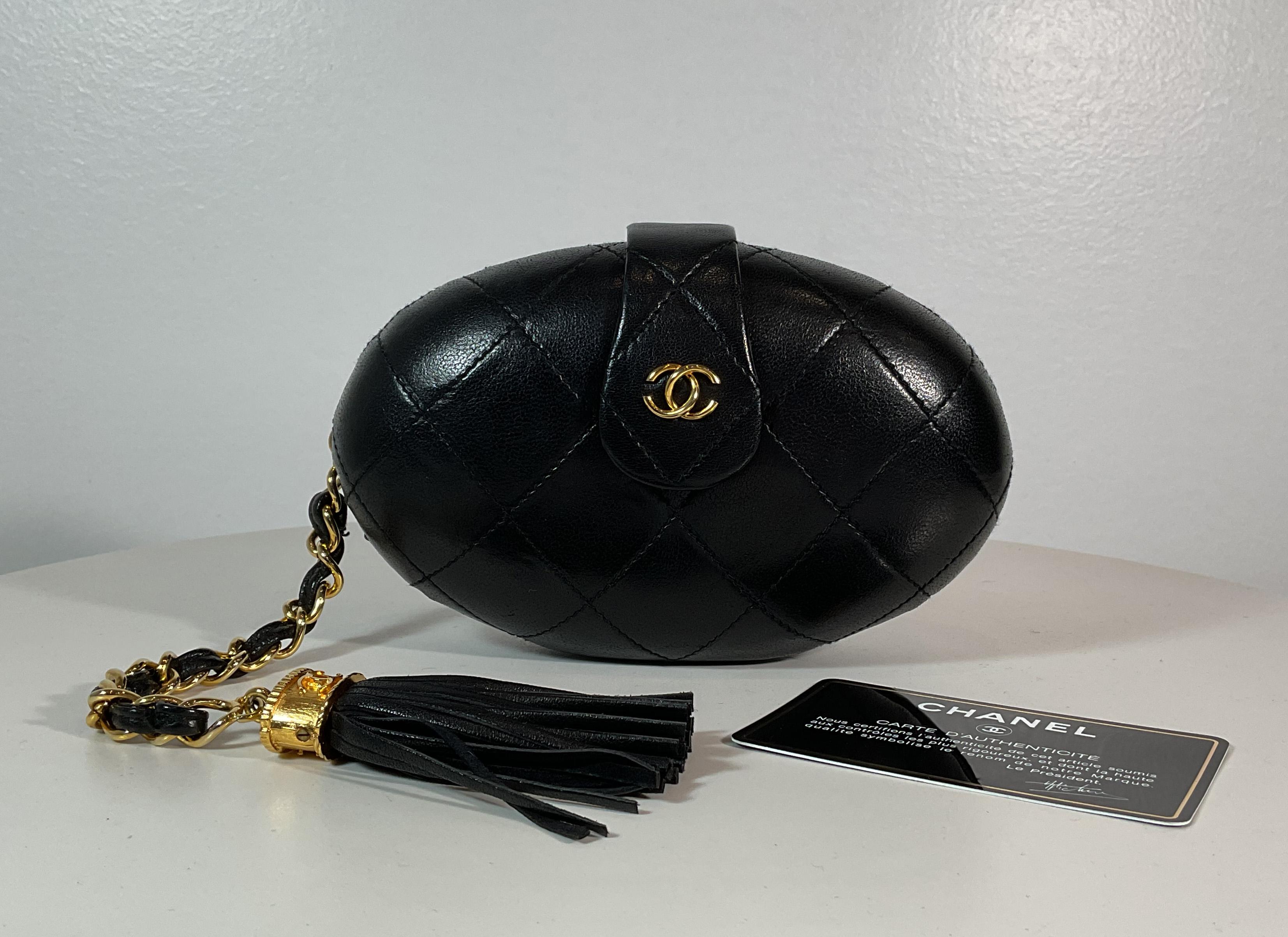 Chanel vintage black lambskin quilted leather oval clutch with logo tassel accent. This clutch comes with its original authenticity card and dust bag. It's in great condition and appears to have never been used. There is only the very slightest