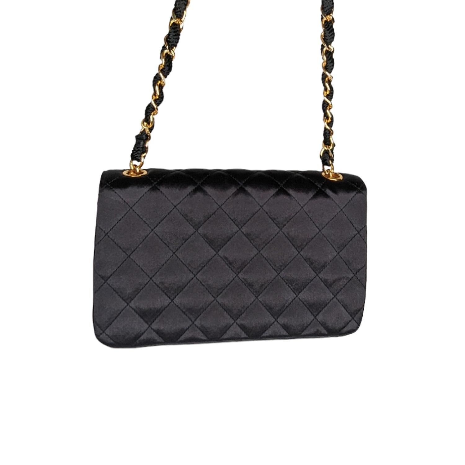 This is a chic mini shoulder bag that is finely crafted of black diamond quilted satin fabric. The bag features a gold chain link and fabric shoulder strap and a CC turn-lock opens to a tonal satin interior with a slip pocket. This is an excellent